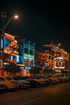 Vibrant urban scene with neon-lit buildings and parked cars during nighttime in Asia.