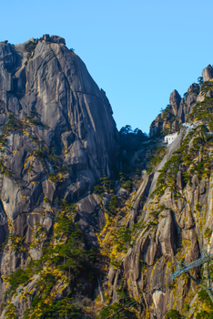 Breathtaking view of Huangshan mountain peaks with steep cliffs and clear blue sky.