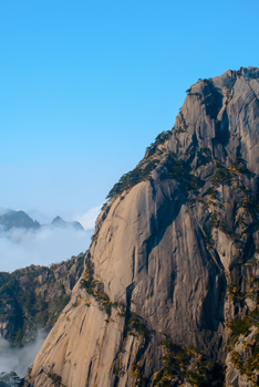 Stunning view of Huangshan Mountains, China, enveloped in mist and clear blue sky.