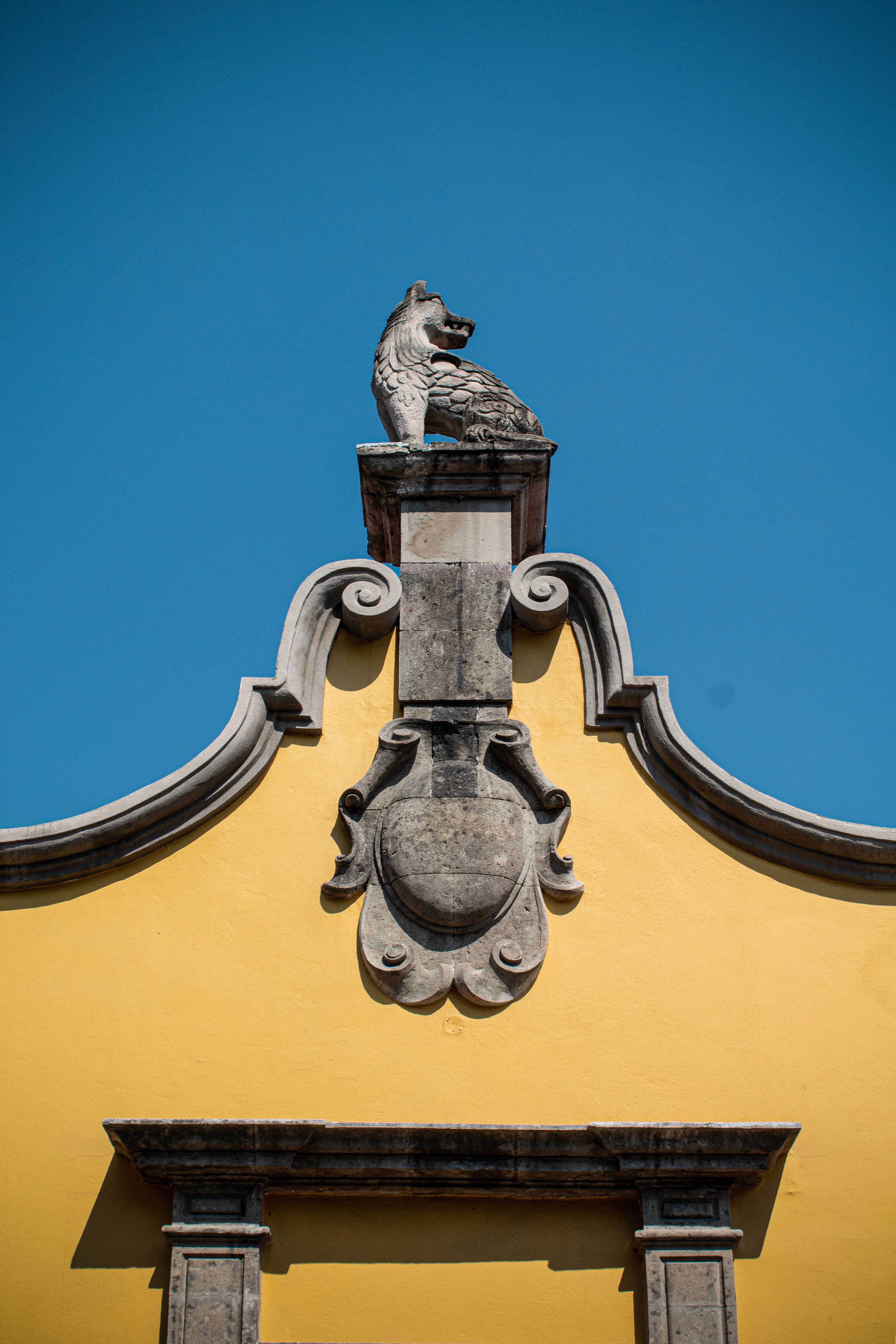 Photograph of a coyote sculpture atop a historic building in Coyoacán, Mexico City.