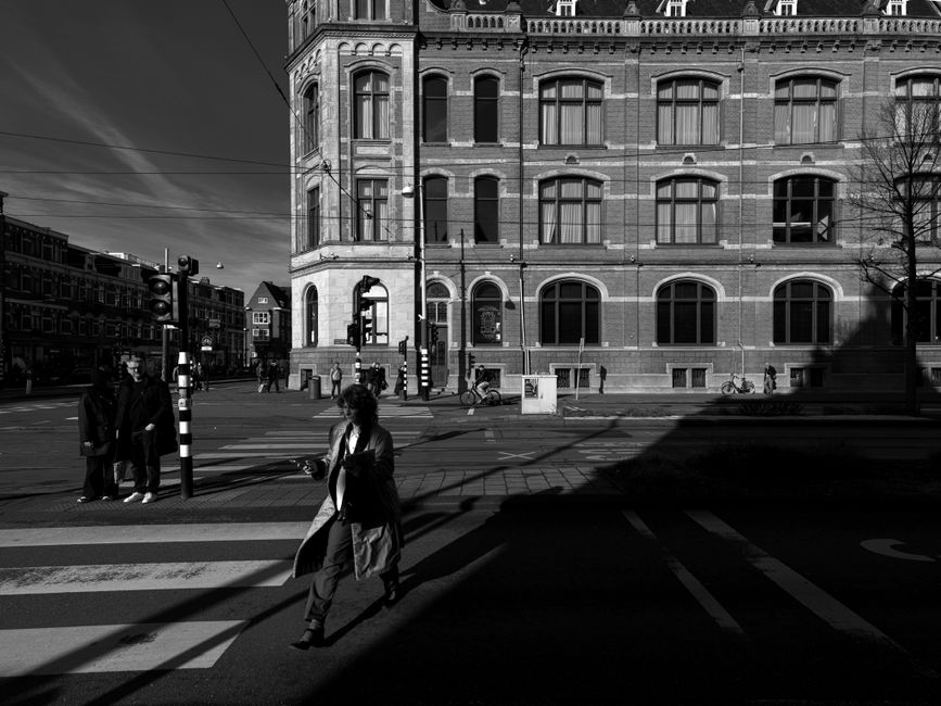 Black and white street scene depicting people and historic architecture in Amsterdam.