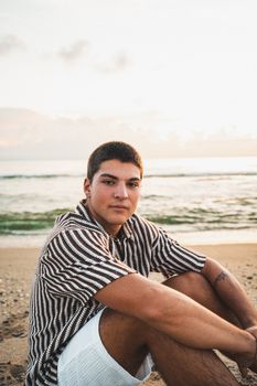 A young man sits on Melbourne Beach, Florida, enjoying a peaceful sunset by the sea.