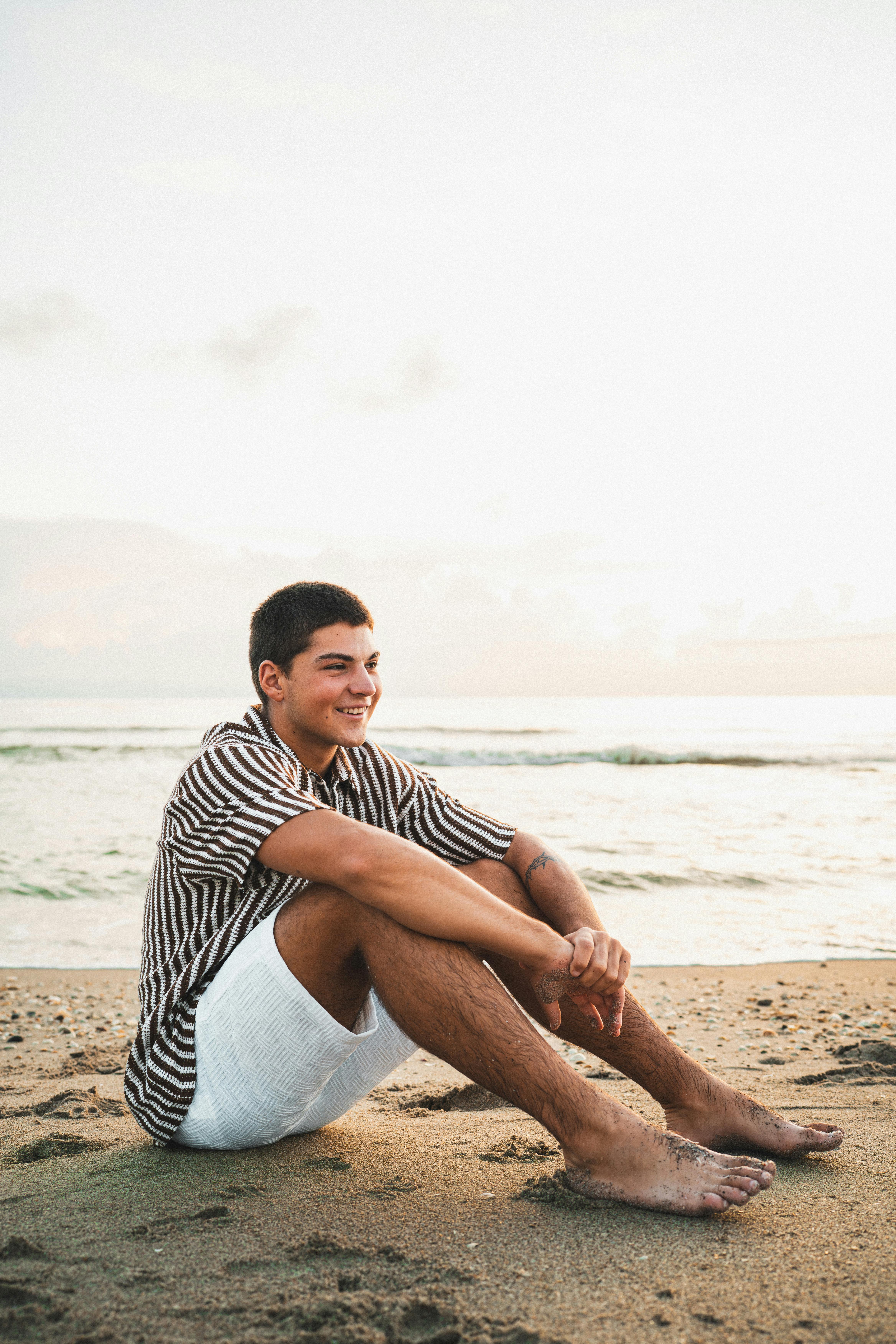 Безкоштовне Молодий чоловік сидить на пляжі Мельбурна, Флорида, насолоджуючись безтурботним заходом сонця. стокове фото