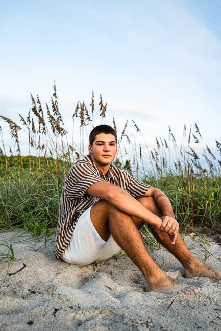 Young man relaxing on the sand at Melbourne Beach, Florida during sunset.