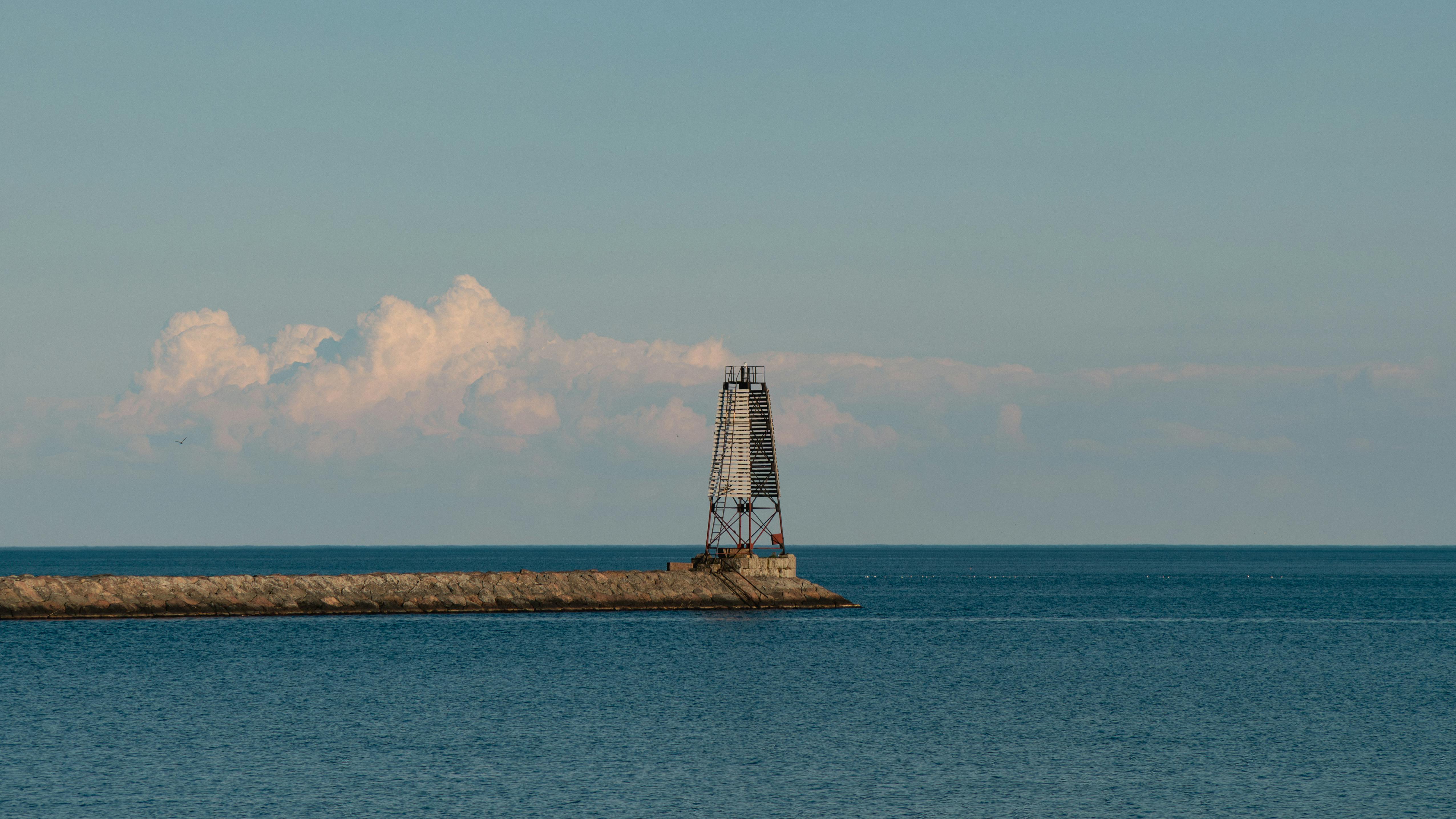Gratis Fredelig utsikt over et fyrtårn på en brygge i St. Petersburg, Russland, mot et rolig hav og en rolig himmel. Arkivbilde