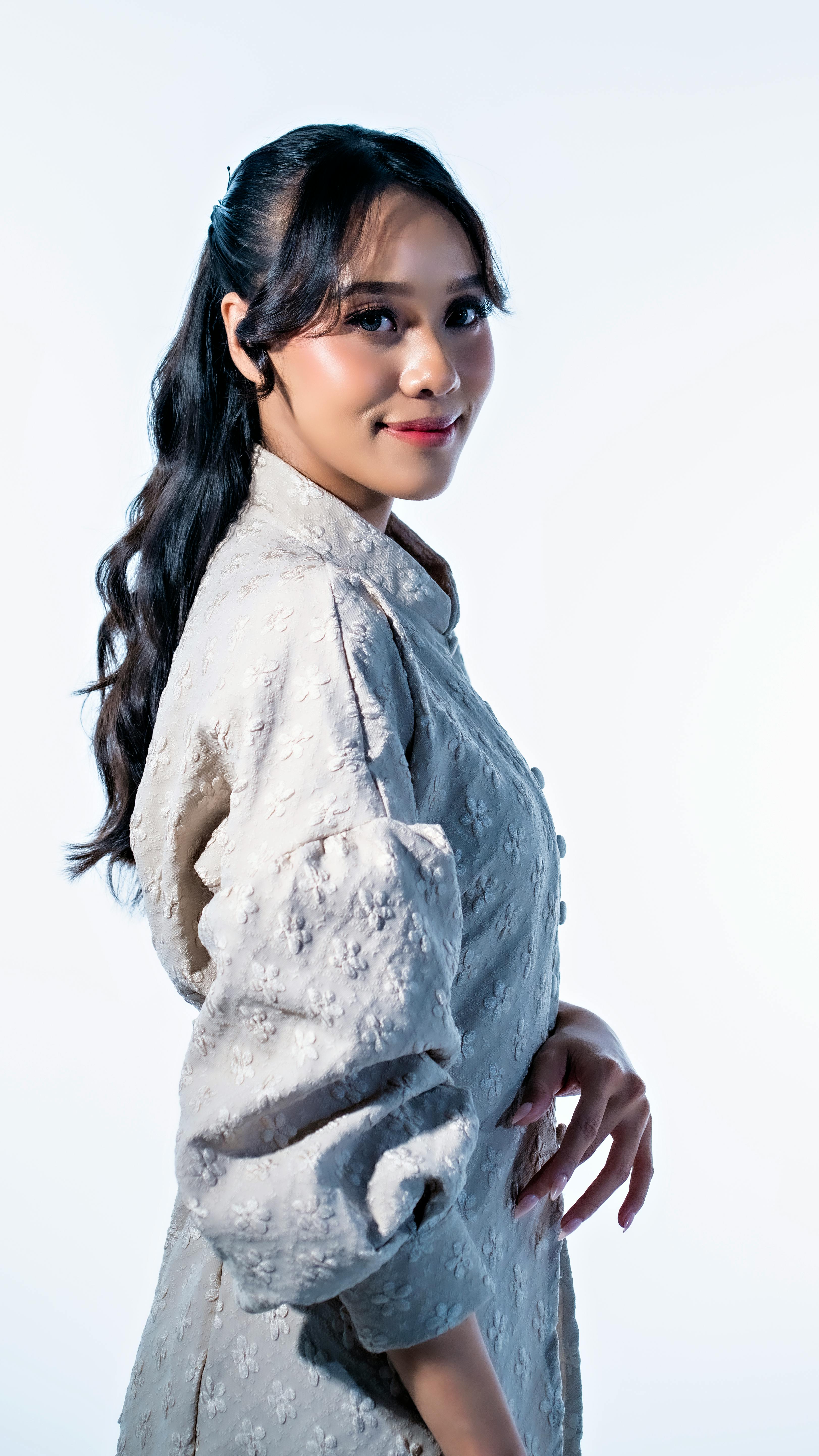 ingyenes Portré egy mosolygós nőről világos, elegáns ruhában, semleges háttér előtt. Stockfotó