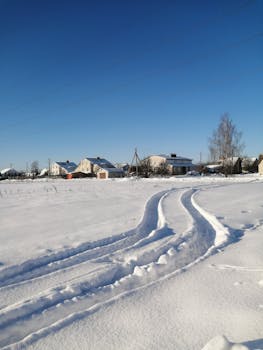 A beautiful winter scene featuring a snow-covered village under a clear blue sky.