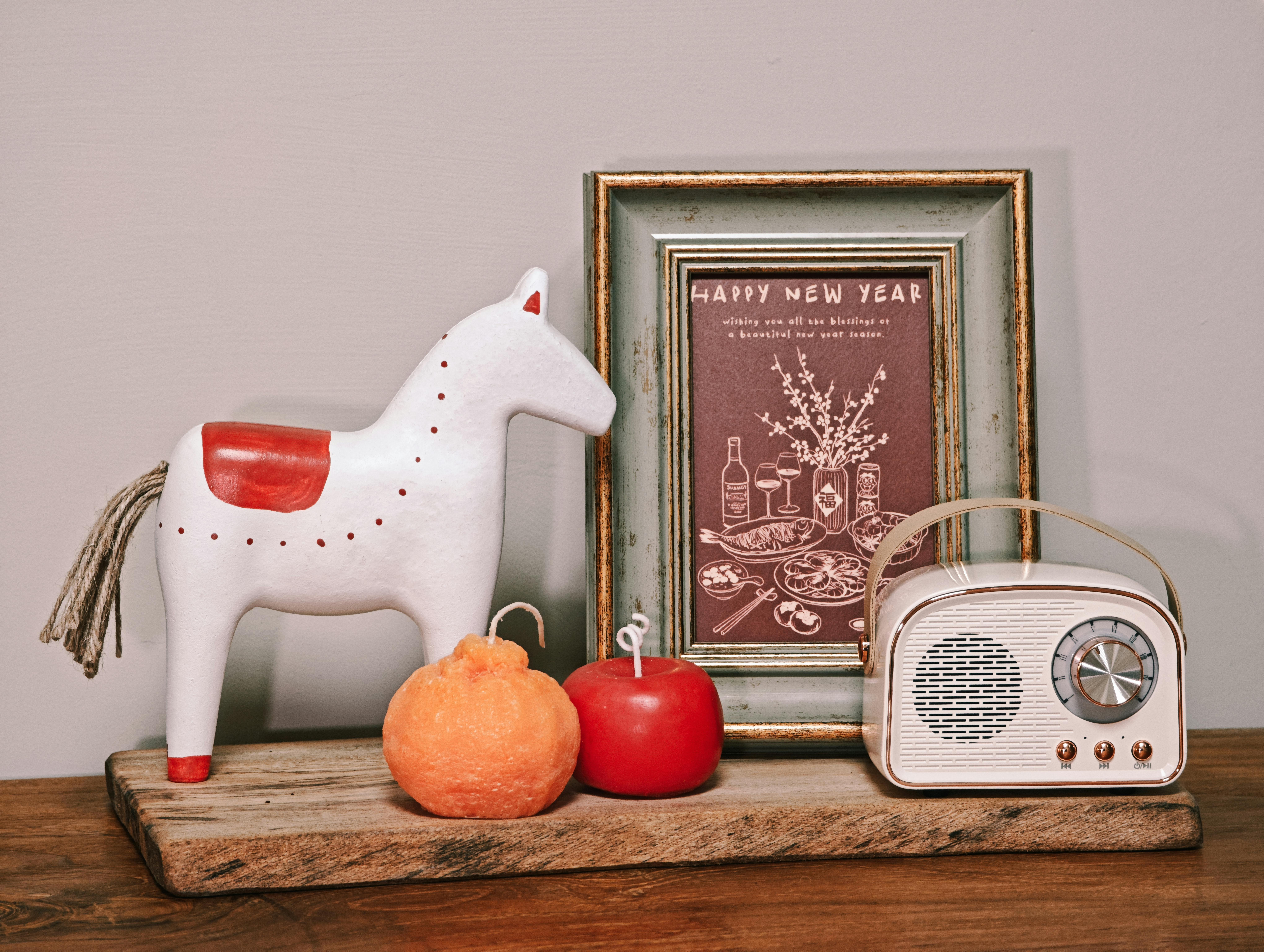 Gratis Sebuah susunan menawan yang menampilkan dekorasi meriah dengan ornamen kuda, ucapan Tahun Baru, dan radio antik di atas rak kayu. Foto Stok