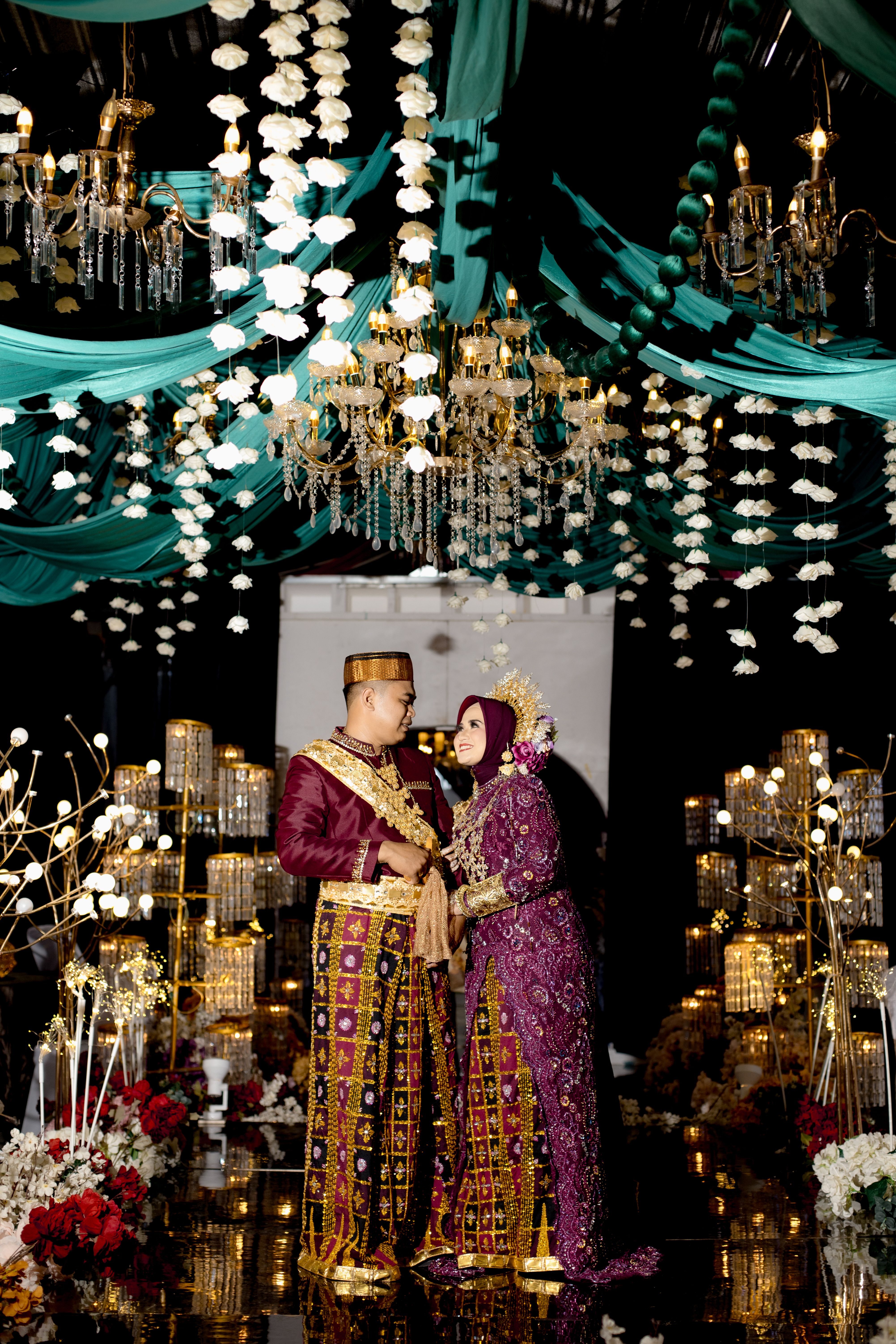 Couple in traditional Indonesian attire at a beautifully decorated wedding in Kendari.