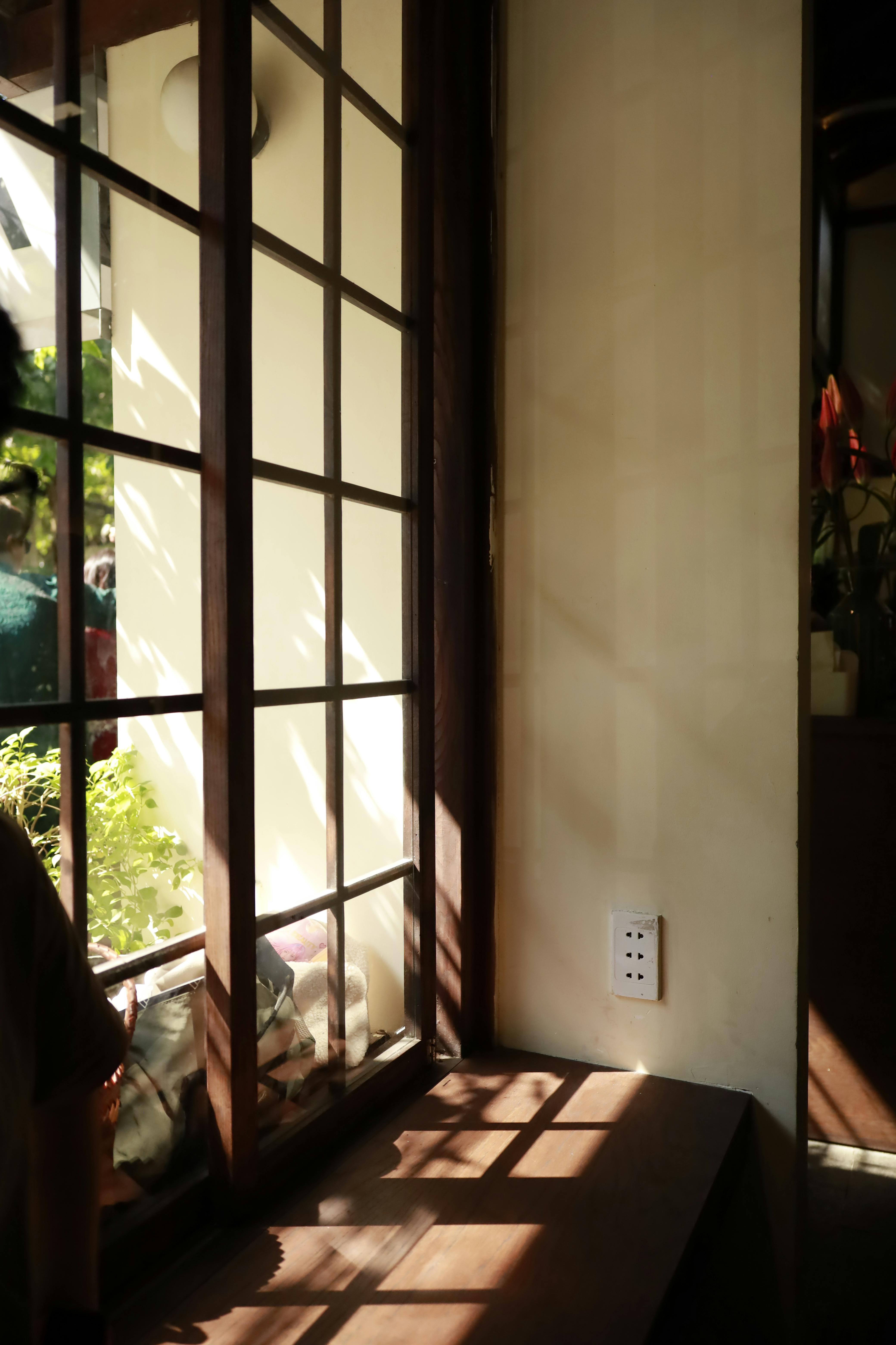 gratis Zonlicht werpt schaduwen door een raam in een Vietnamees huis en creëert zo een serene sfeer. Stockfoto