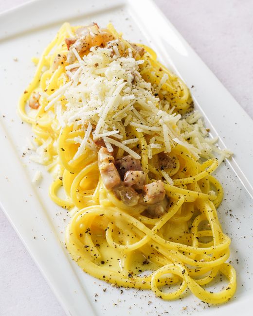 Close-up of creamy carbonara pasta topped with grated cheese, perfect for a gourmet food presentation.