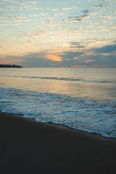 Serene view of Hampton Beach at sunset with gentle waves and colorful sky.