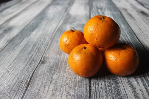 Free A stack of fresh oranges on a rustic wooden surface, showcasing their vibrant color and texture. Stock Photo
