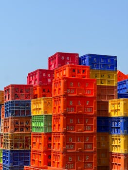 Colorful plastic crates stacked high under a clear blue sky, forming a vivid pattern.