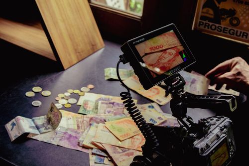 Free Film setup on table with mixed currency notes and coins, artistic shot. Stock Photo