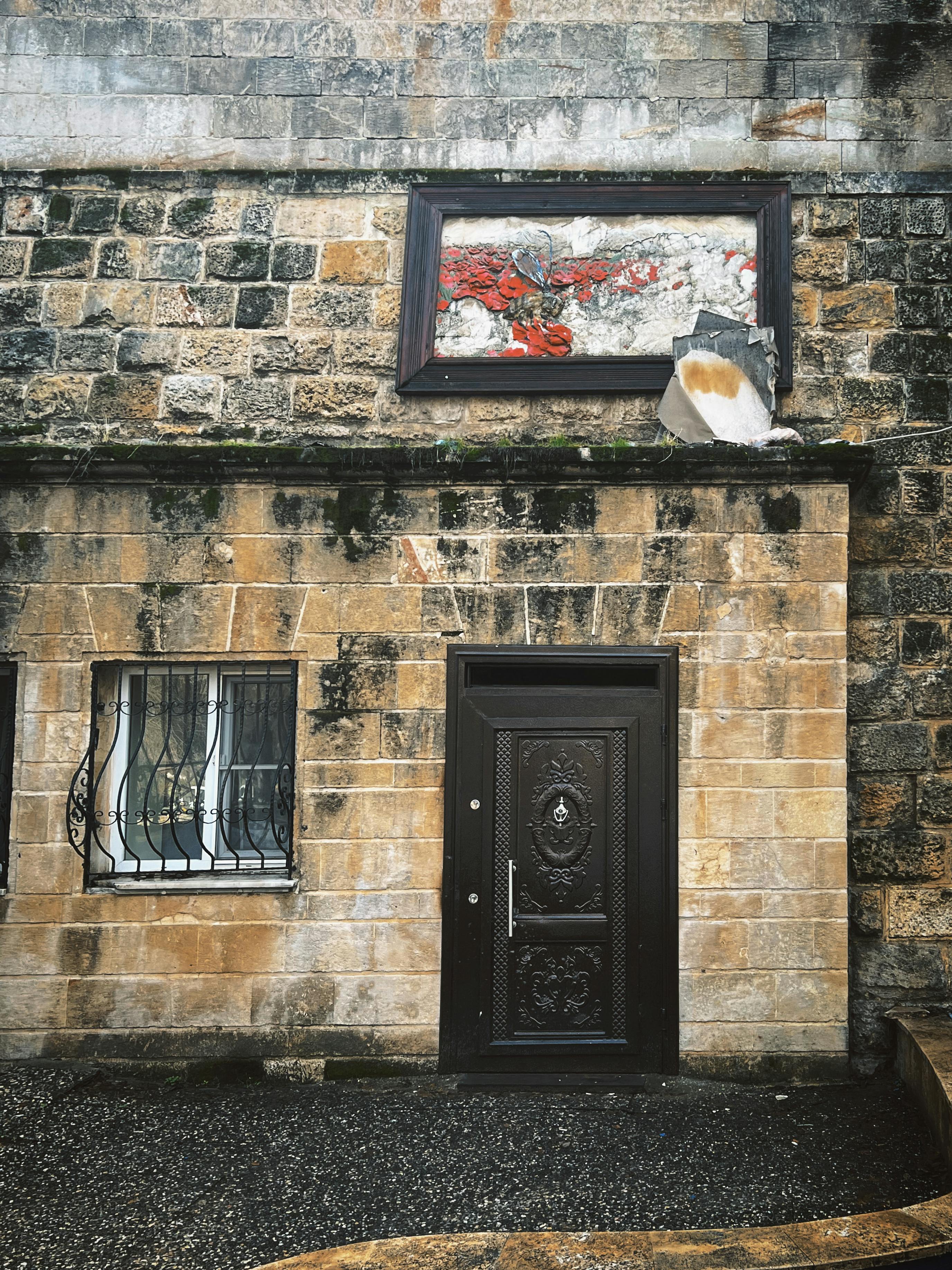 ingyenes Egy régi kőépület homlokzata díszes vasajtóval és ablakrácsokkal, rusztikus bájt kölcsönözve. Stockfotó