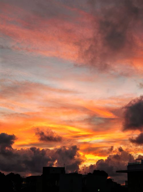 Free Stunning sunset with vibrant clouds silhouetted against an urban skyline. Stock Photo