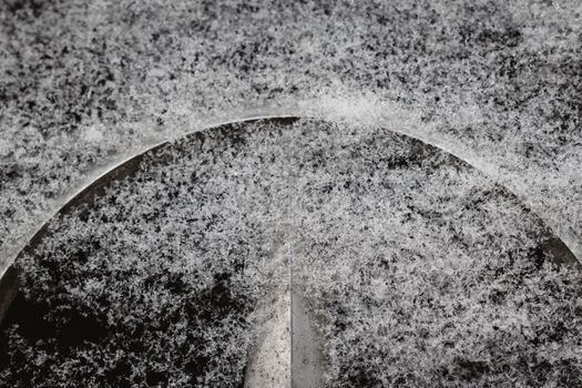 Detailed macro image of snowflakes covering a metal car wheel rim in winter conditions.