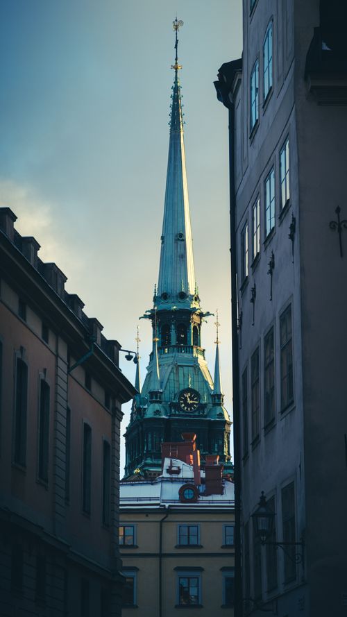 Free Elegant Storkyrkan spire rising above Stockholm's historic streets, beautifully lit. Stock Photo