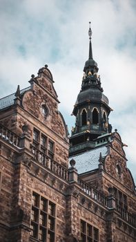 Historic Nordic Museum tower with intricate architecture under a cloudy Stockholm sky.