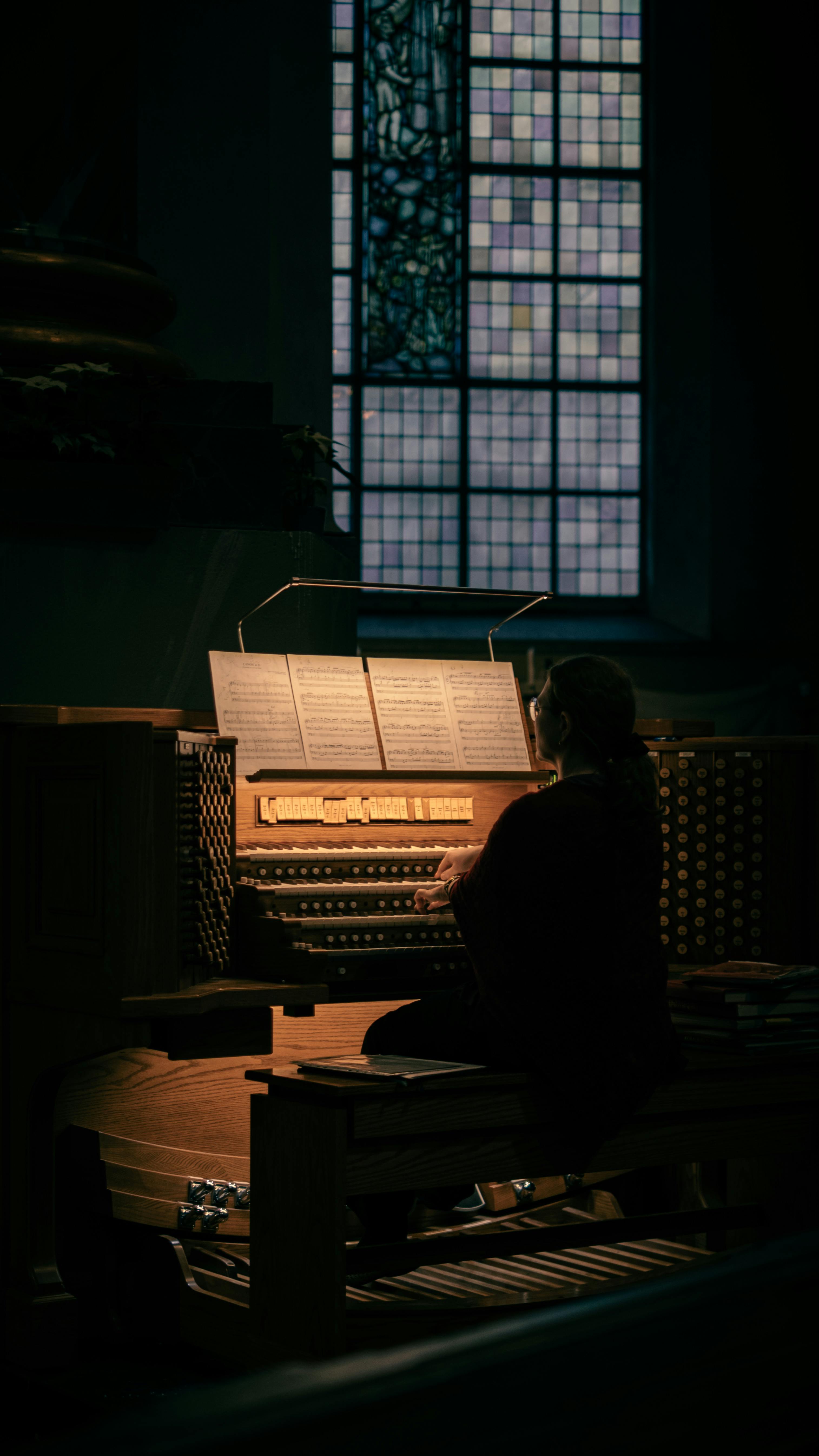 Gratis En musiker spiller orgel i en svakt opplyst kirke i Stockholm, noe som skaper en rolig atmosfære. Arkivbilde