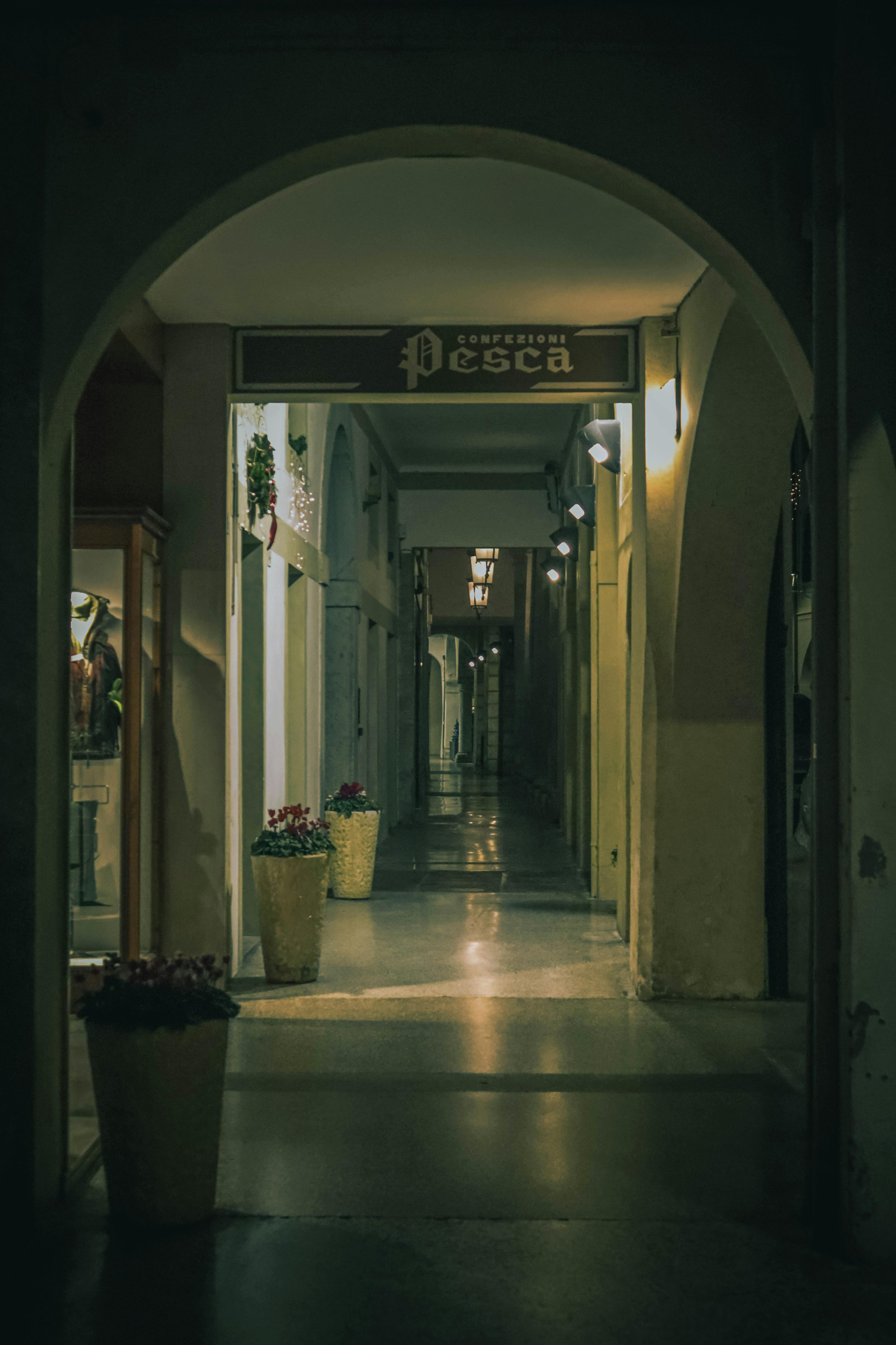 Ücretsiz Gece aydınlatıldığında hüzünlü bir atmosfer yaratan kemerli geçitlere sahip sakin bir ara sokak. Stok Fotoğraflar