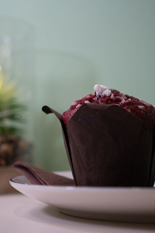 Free Close-up of a scrumptious red velvet muffin wrapped in paper on a plate. Stock Photo