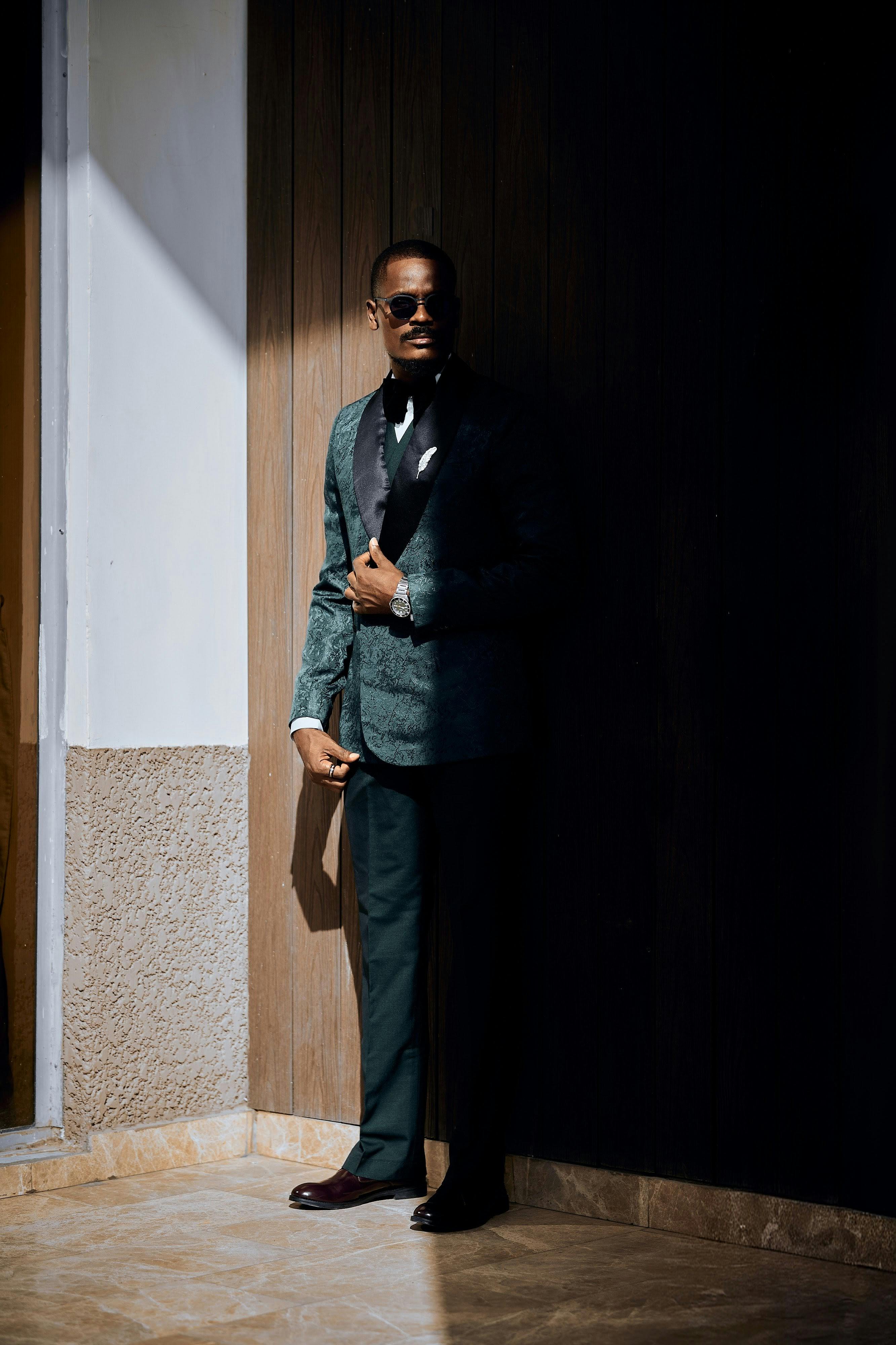 Gratis Un hombre elegante con traje se mantiene seguro en un interior, combinando elegancia y misterio en un entorno sombrío. Foto de stock