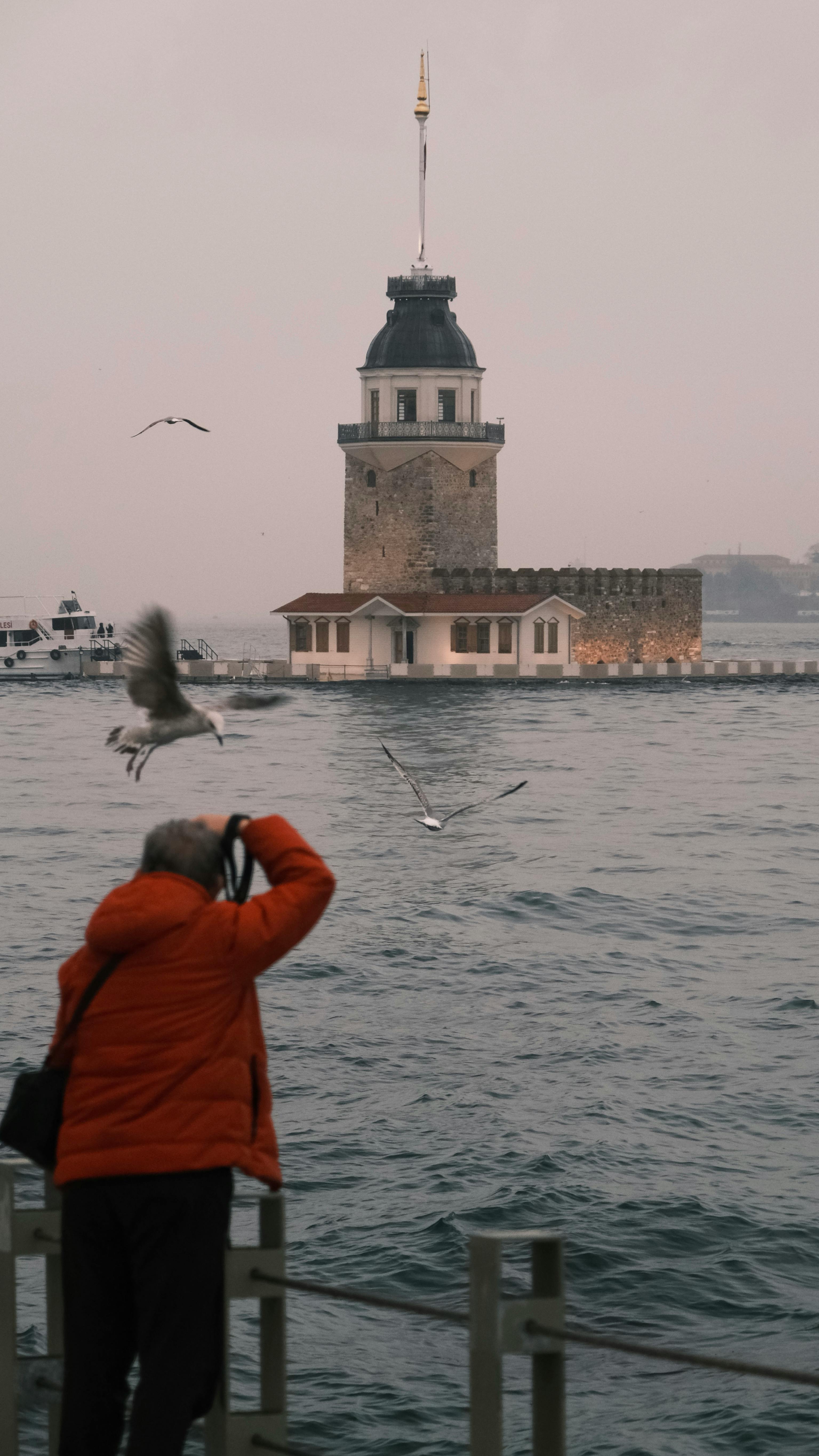 Miễn phí Một nhiếp ảnh gia chụp ảnh tòa tháp Maiden's Tower nổi tiếng với những con mòng biển đang bay lượn ở Istanbul, Thổ Nhĩ Kỳ. Ảnh lưu trữ