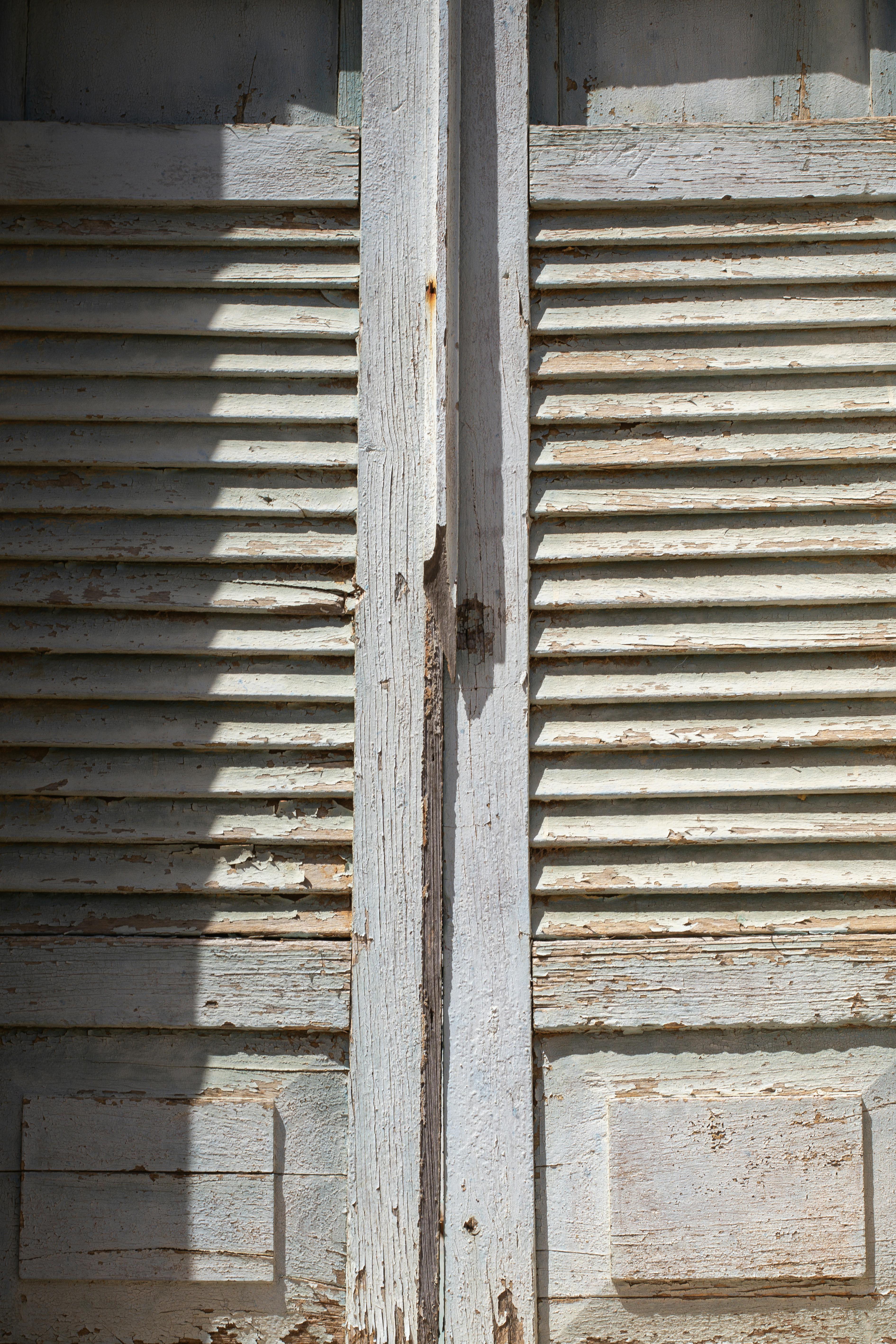 Kostenlos Nahaufnahme alter Holzfensterläden mit abblätternder Farbe, die Textur und Details zeigt. Stock-Foto