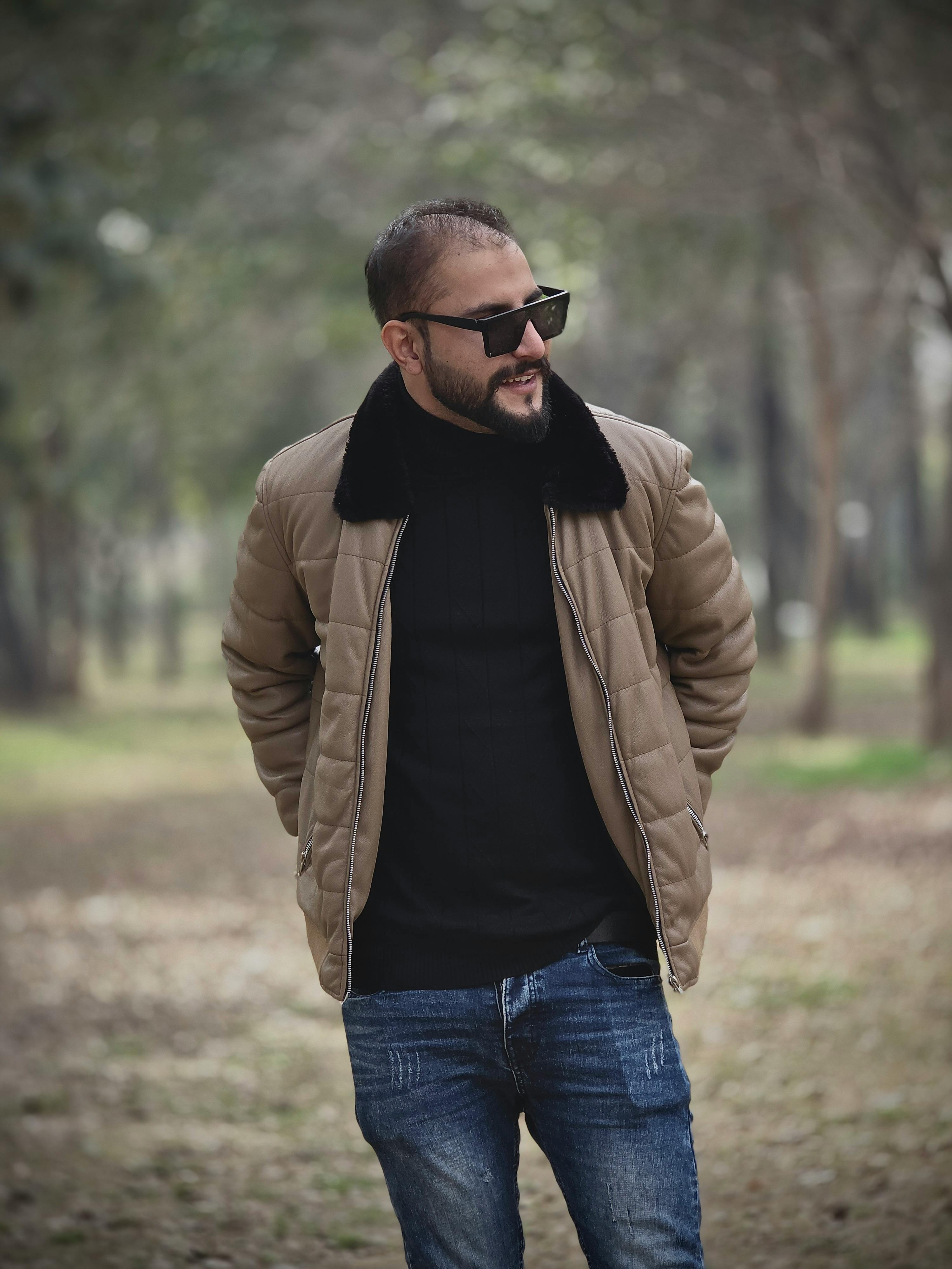 gratis Een man met een jas en zonnebril loopt in een park tijdens de herfst. Stockfoto