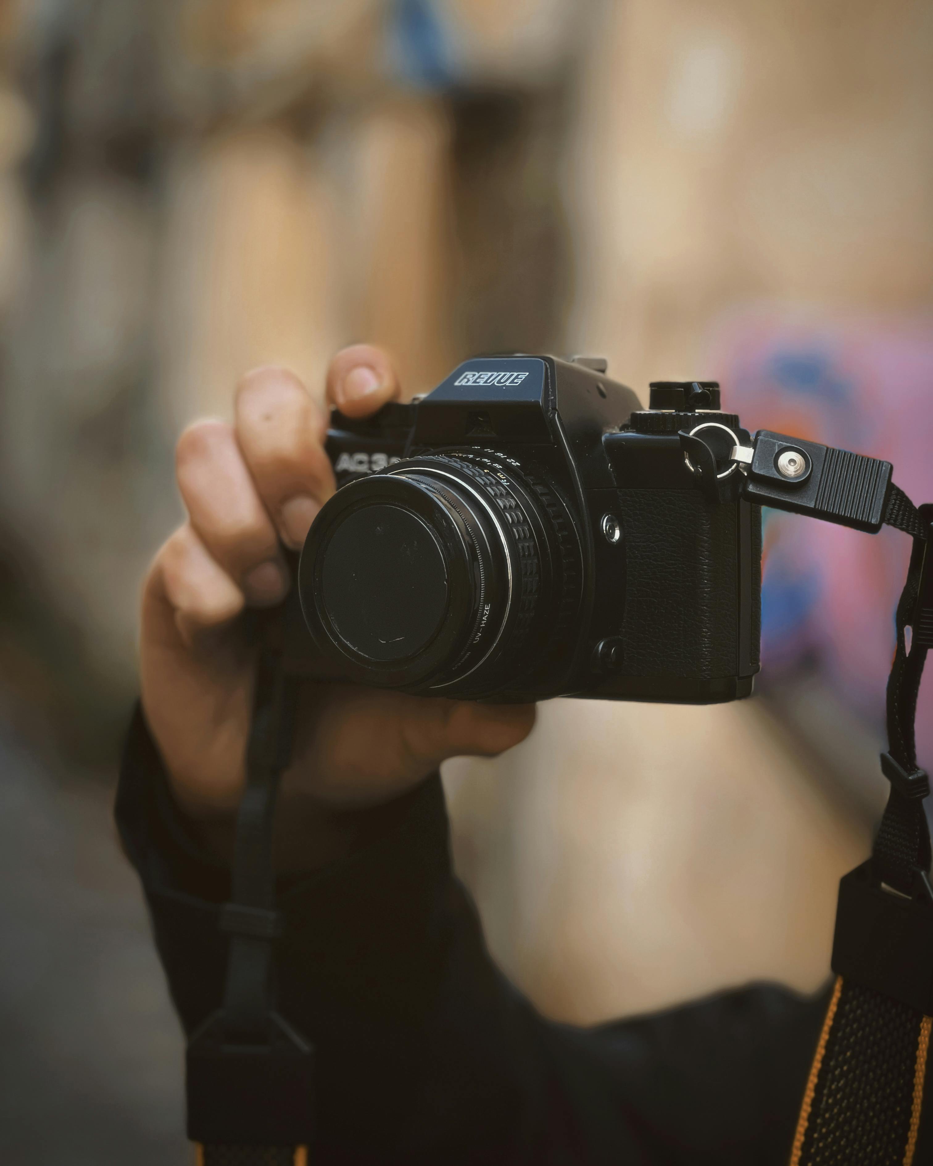 Zadarmo Detailný záber ruky držiacej starožitný fotoaparát, zaostrujúci vonku. Ideálne pre fotografické témy. Fotka z fotobanky