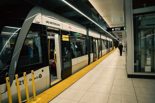 Interior of a Toronto subway station with a Metrolinx train and passengers boarding.