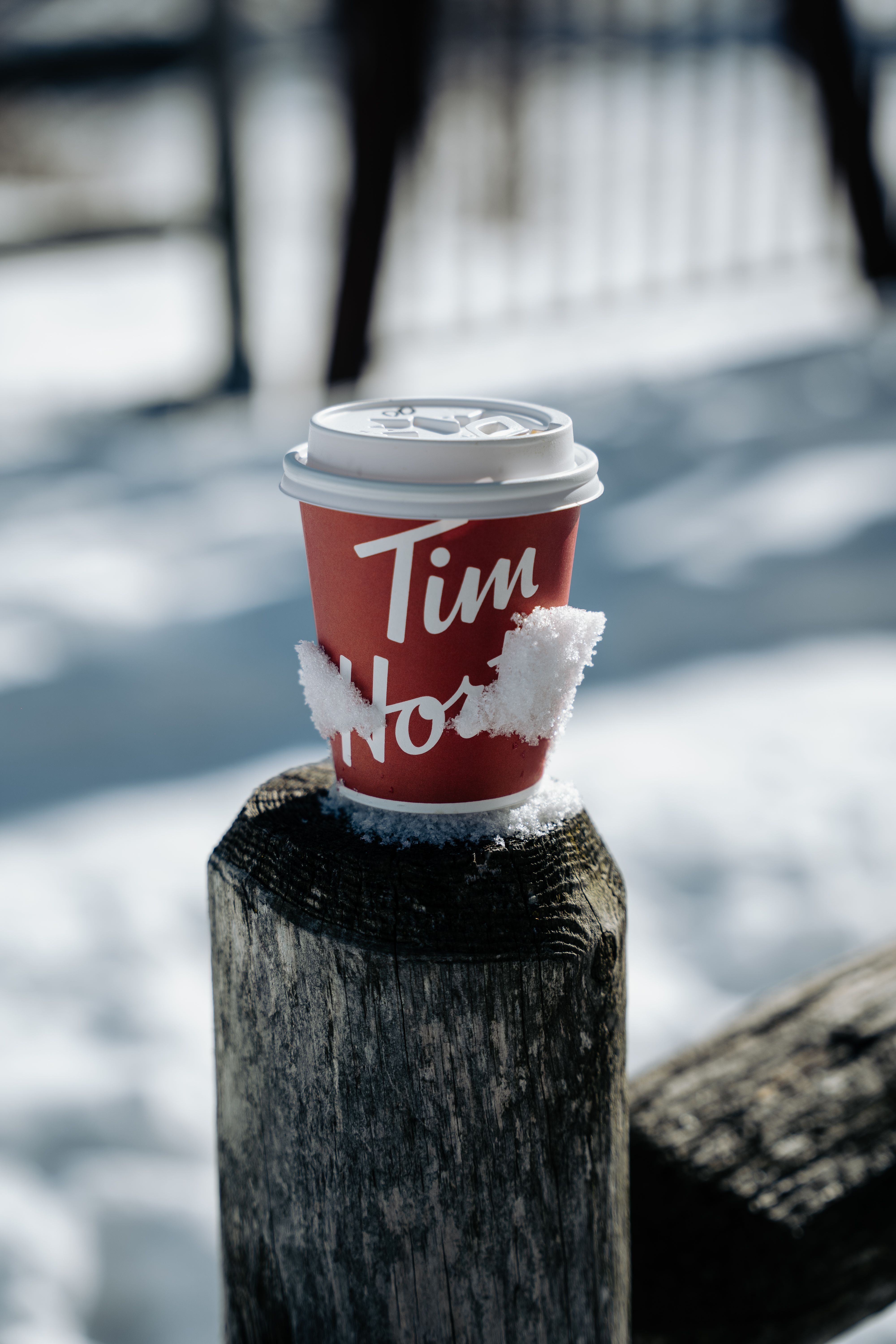 A red branded coffee cup with snow in an outdoor winter scene.