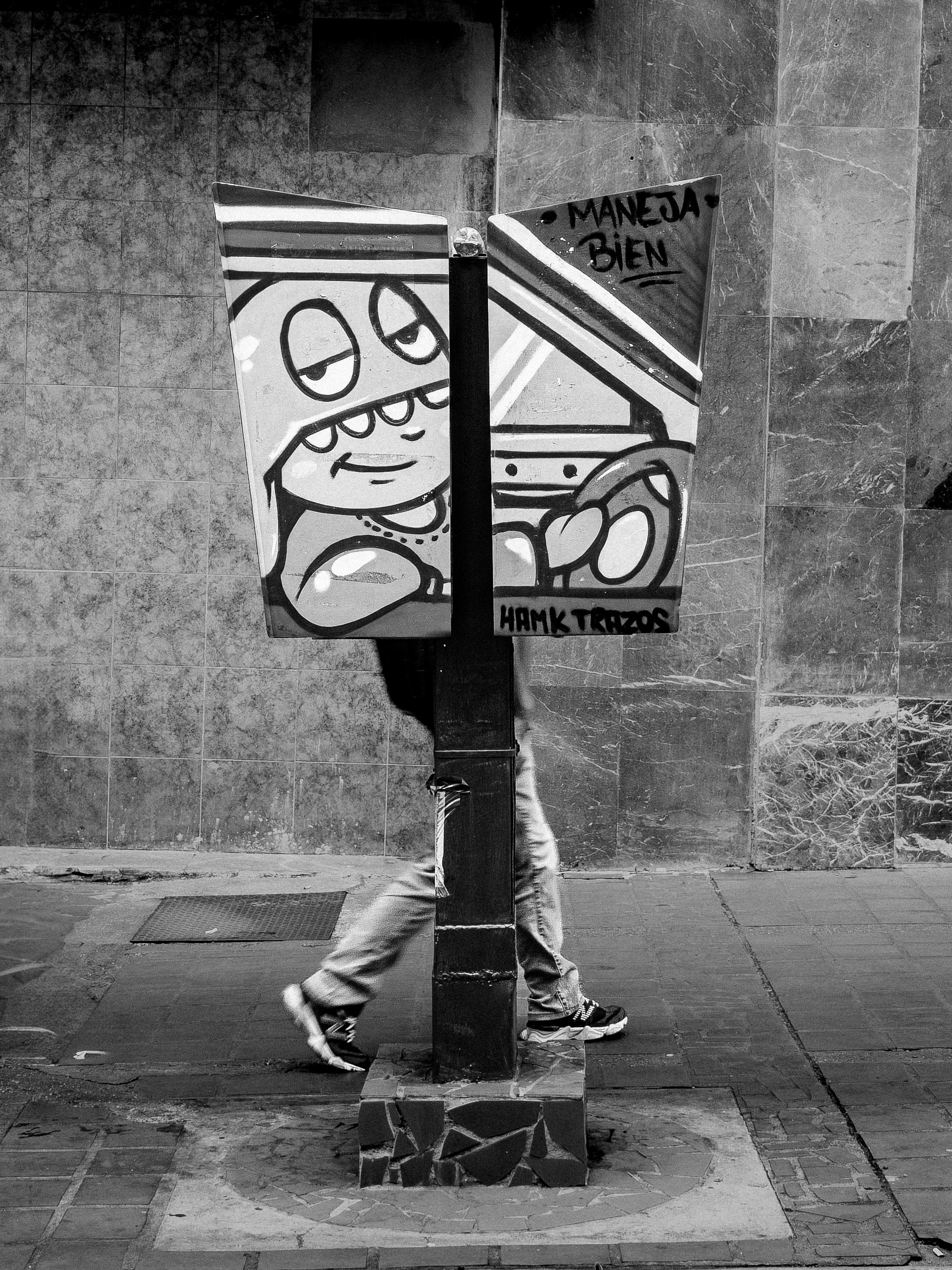 Kostenlos Schwarz-Weiß-Fotografie, die Straßenkunst und einen Fußgänger in Caracas zeigt und eine urbane Szene evoziert. Stock-Foto