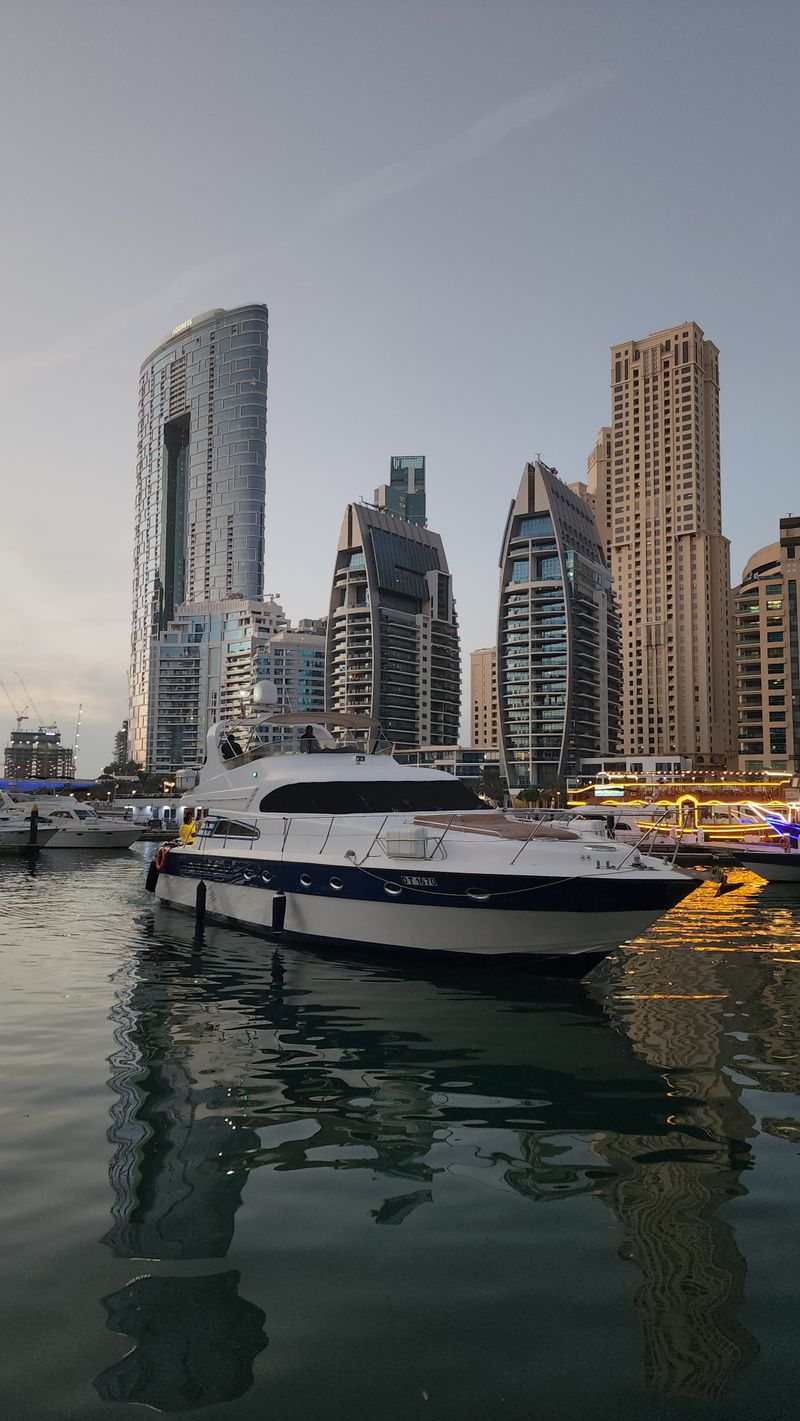 Private motor yacht moored in Dubai Marina at twilight, with towers behind