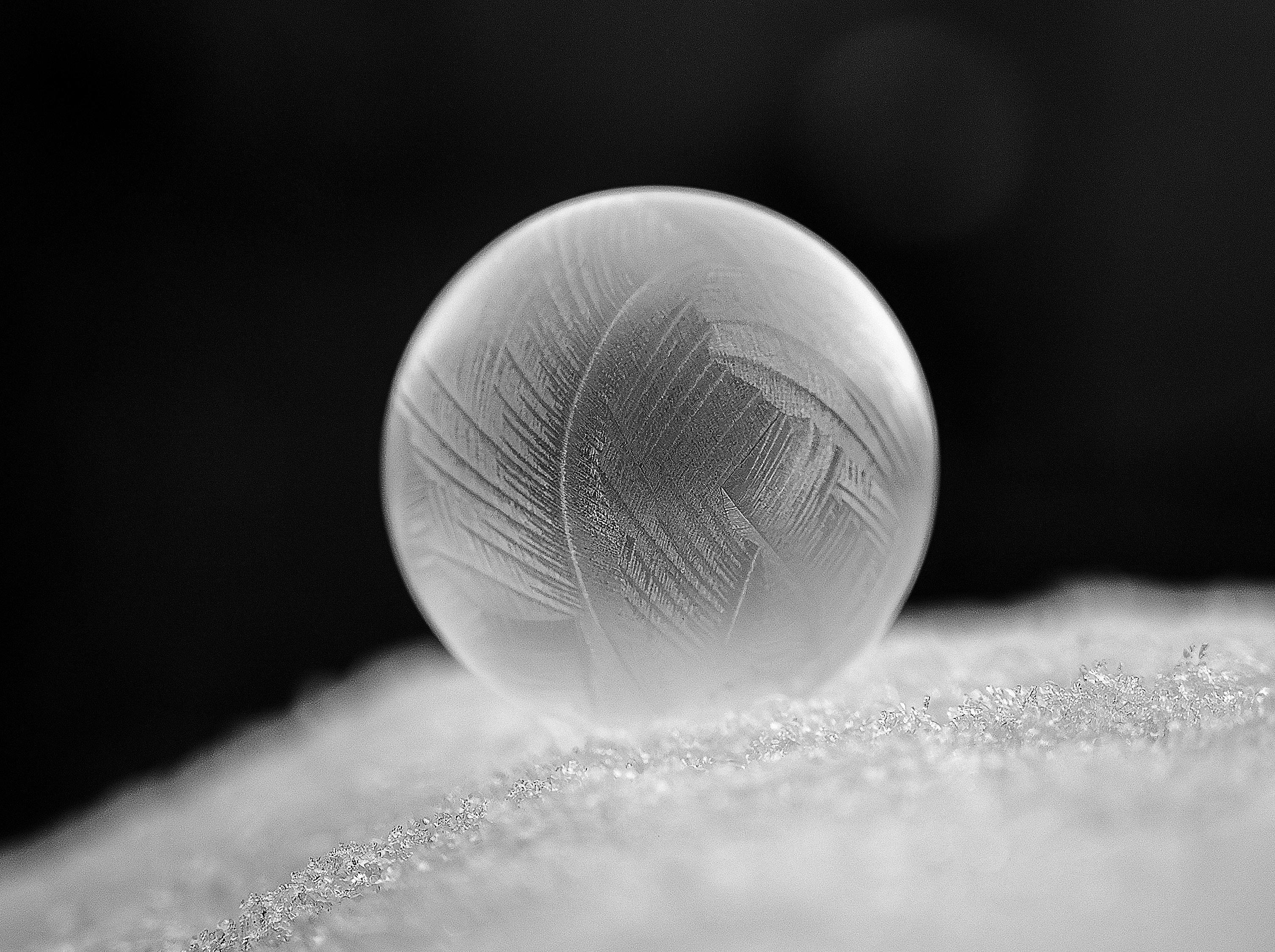 gratis Een bevroren bubbel met ingewikkelde patronen, rustend op sneeuw, die de schoonheid van de winter laat zien. Stockfoto