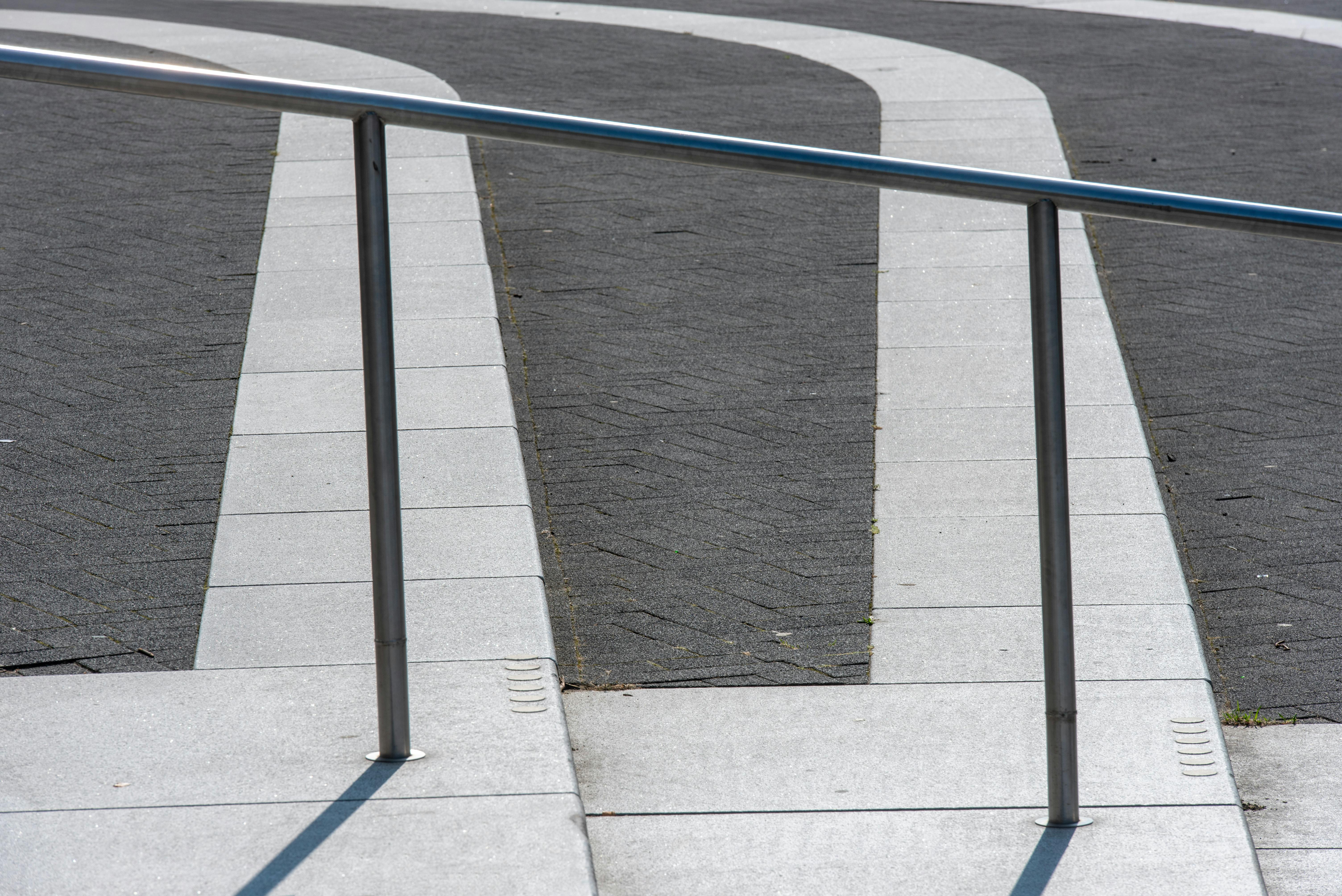 gratis Een strakke metalen leuning langs een modern, gebogen pad in een stedelijk gebied. Stockfoto