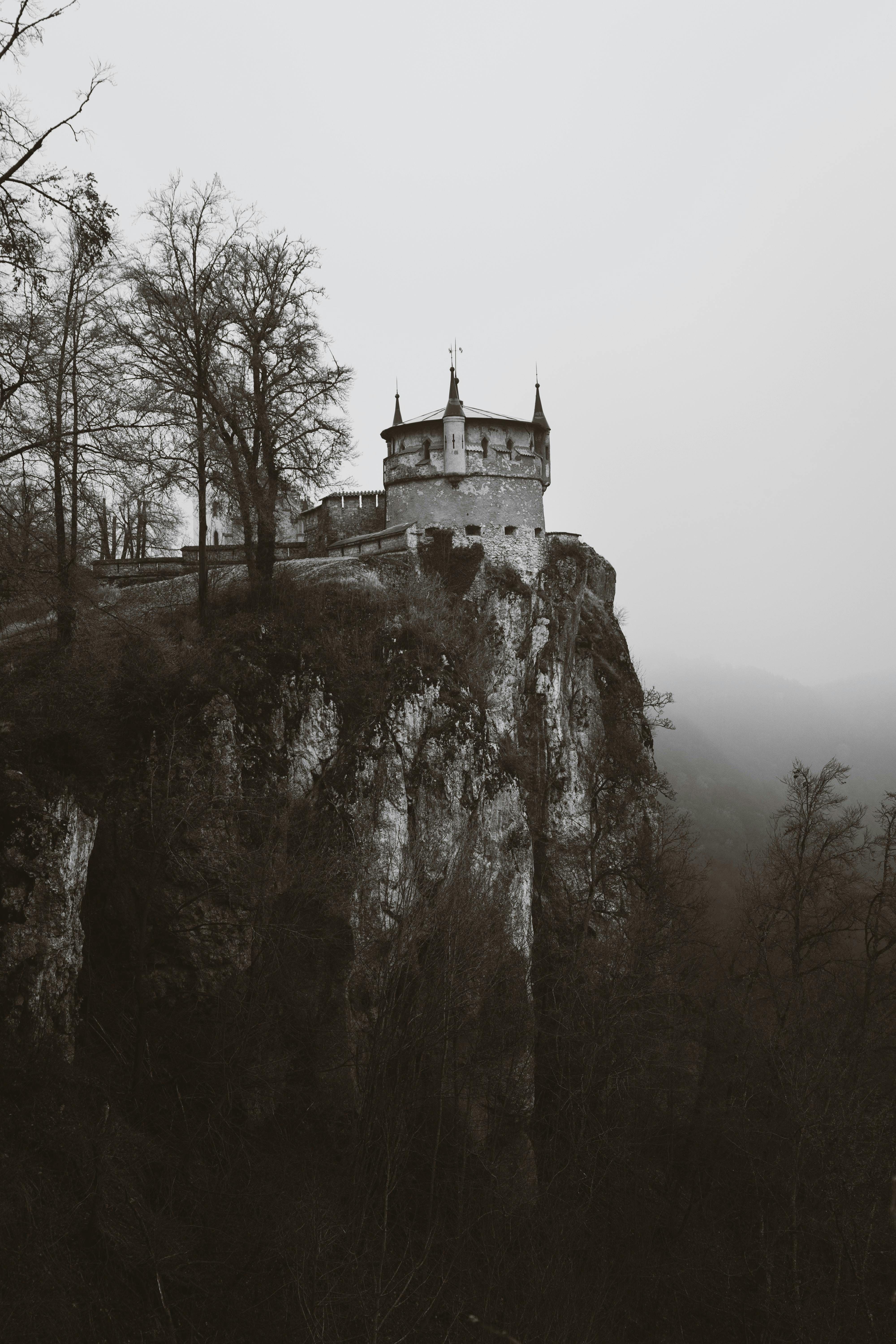 無料 霧に包まれた崖の上に建つ城をドラマチックな白黒トーンで撮影しました。 写真素材