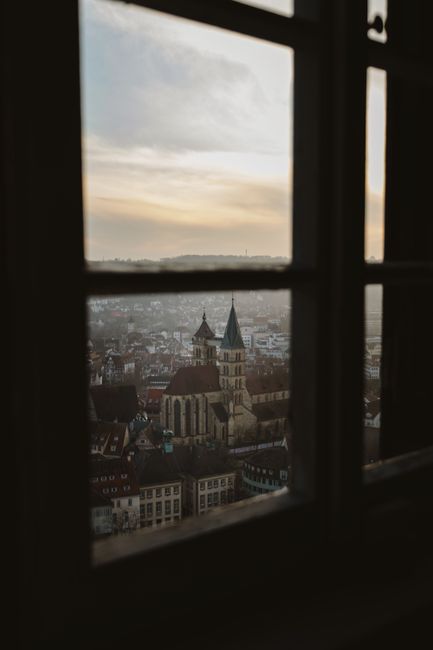 A picturesque view of a gothic-style church amid a cityscape captured through a window at dusk.