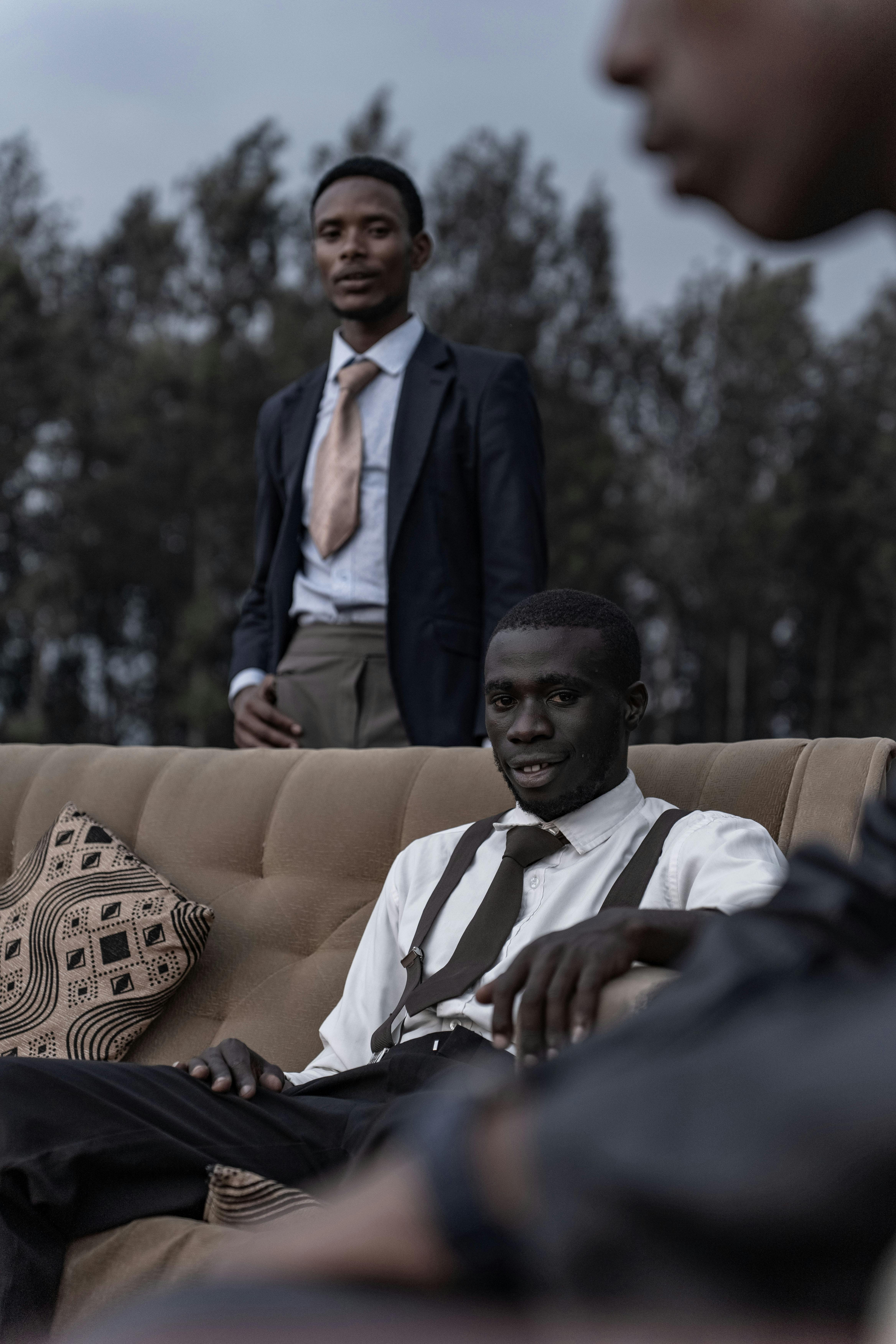 Gratis Tre menn i formelle antrekk poserer for et stilig utendørsportrett. Arkivbilde