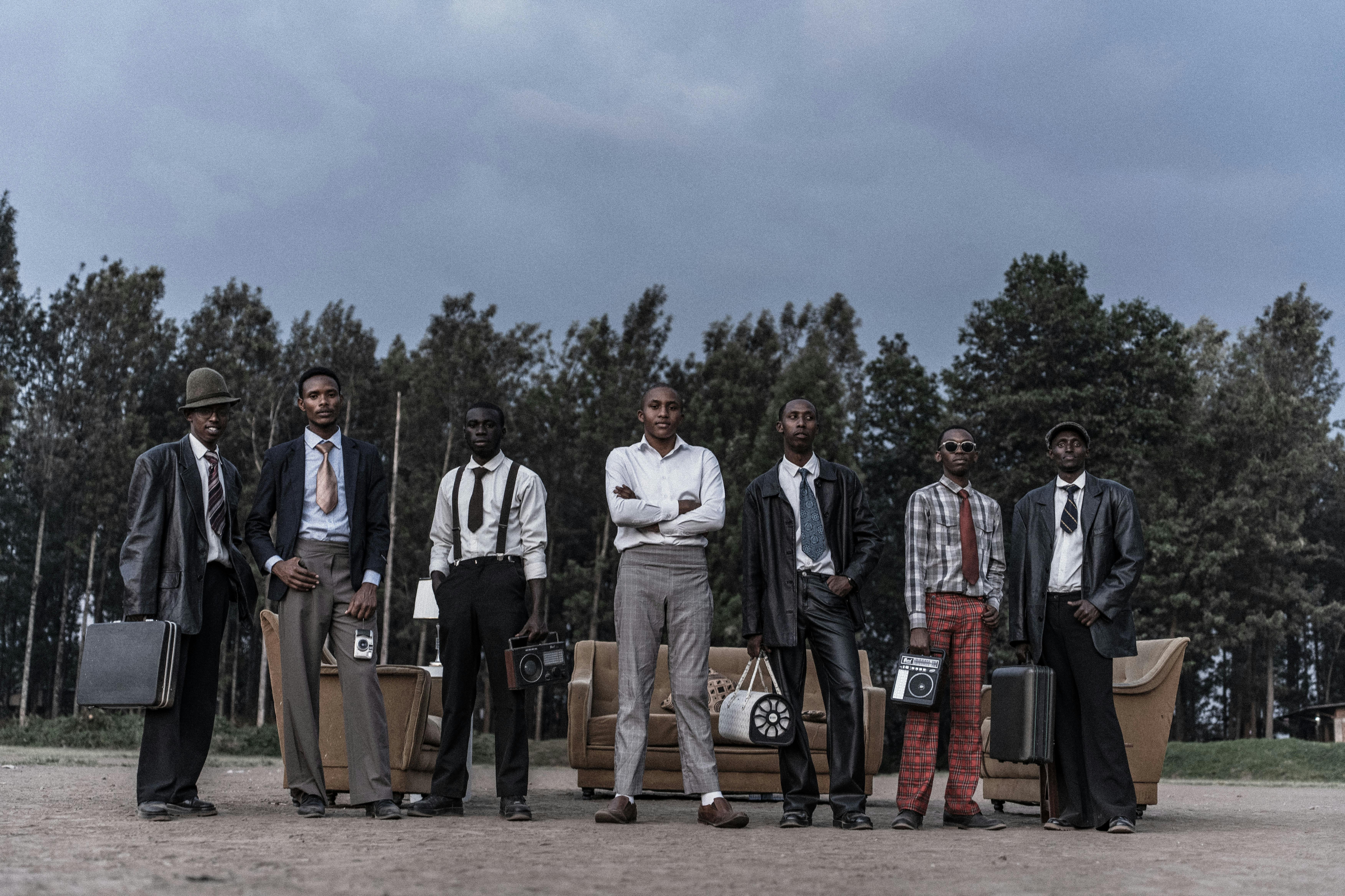 Gratis En gruppe stilige menn i vintage-dresser poserer utendørs med retro kamerautstyr, som utstråler klassisk sjarm. Arkivbilde