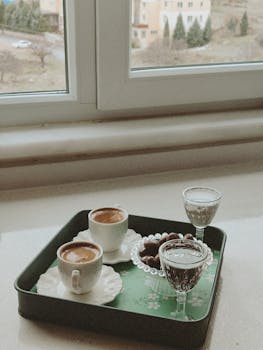 A cozy indoor scene with coffee, treats, and a window view.