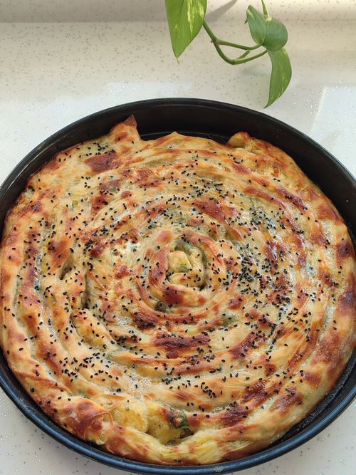 Free Hot spiral-shaped savory pie topped with seeds, freshly baked to golden perfection in a round pan. Stock Photo