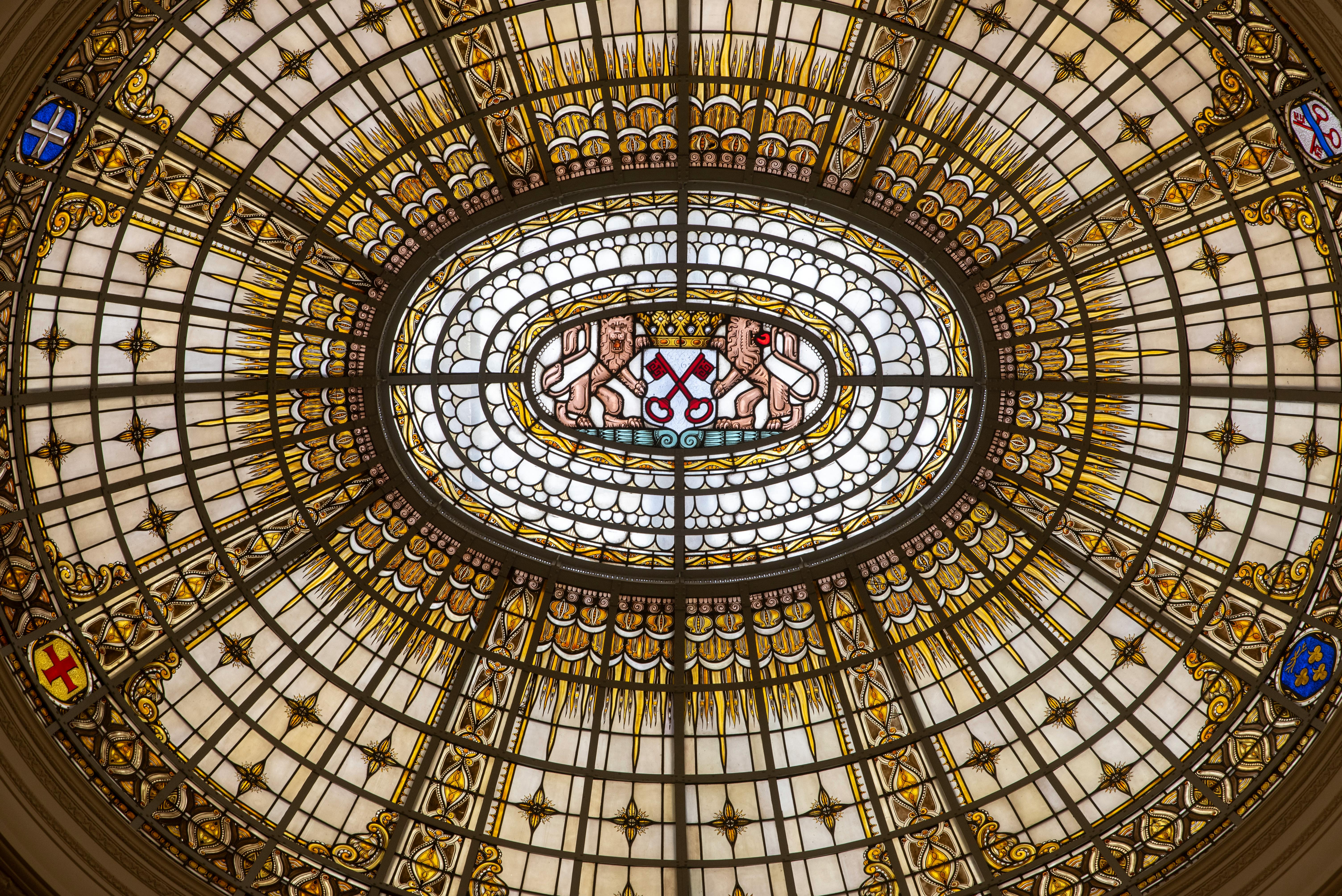 Gratuit Tavan ornamentat cu vitralii, cu accente aurii și o emblemă heraldică centrală. Fotografie de stoc