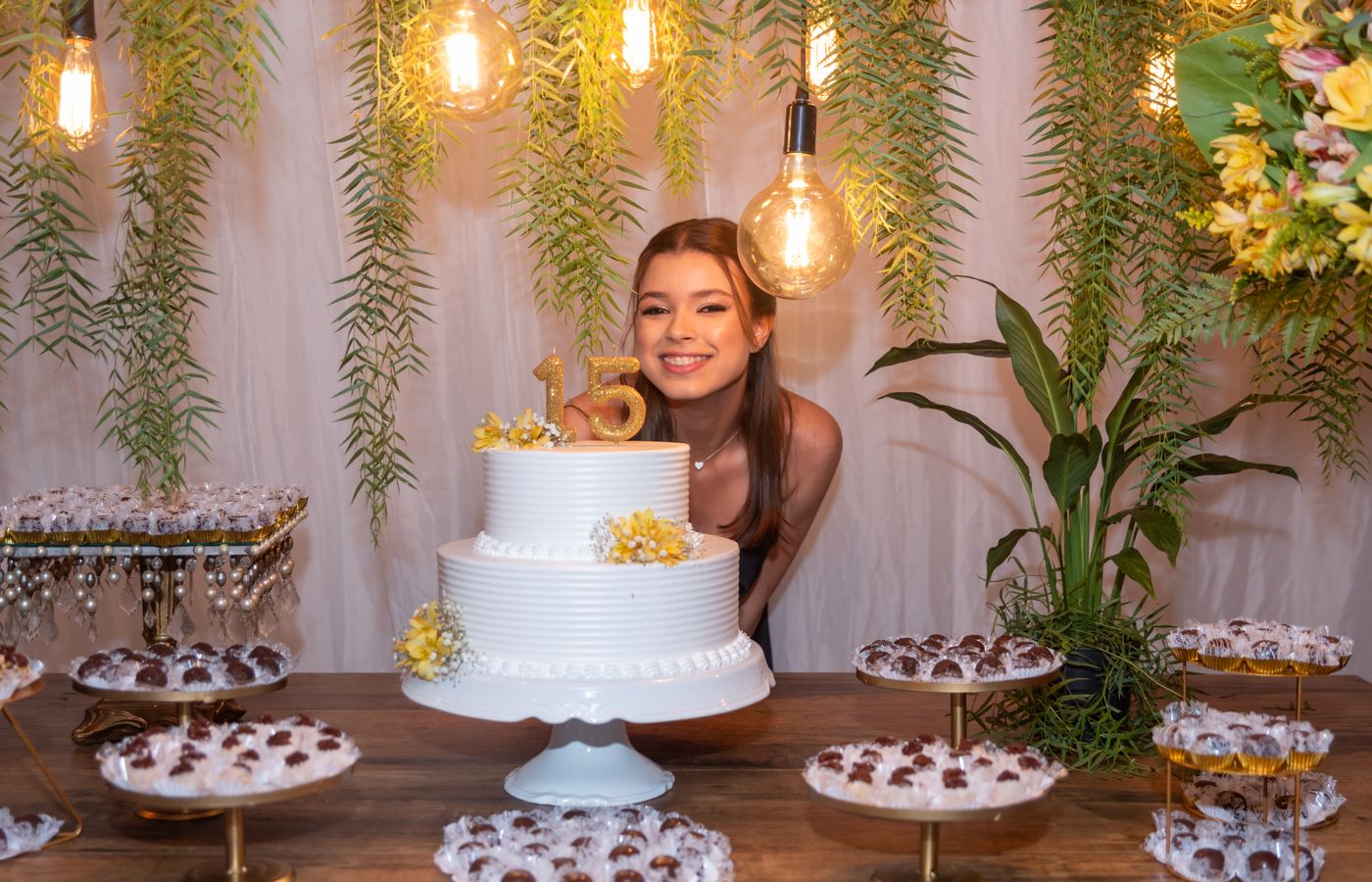 A beautiful indoor quinceañera celebration with cake, floral decor, and a smiling teenage girl.