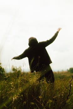 A mysterious figure in a field, silhouetted against a twilight sky, exuding a sense of freedom and adventure.