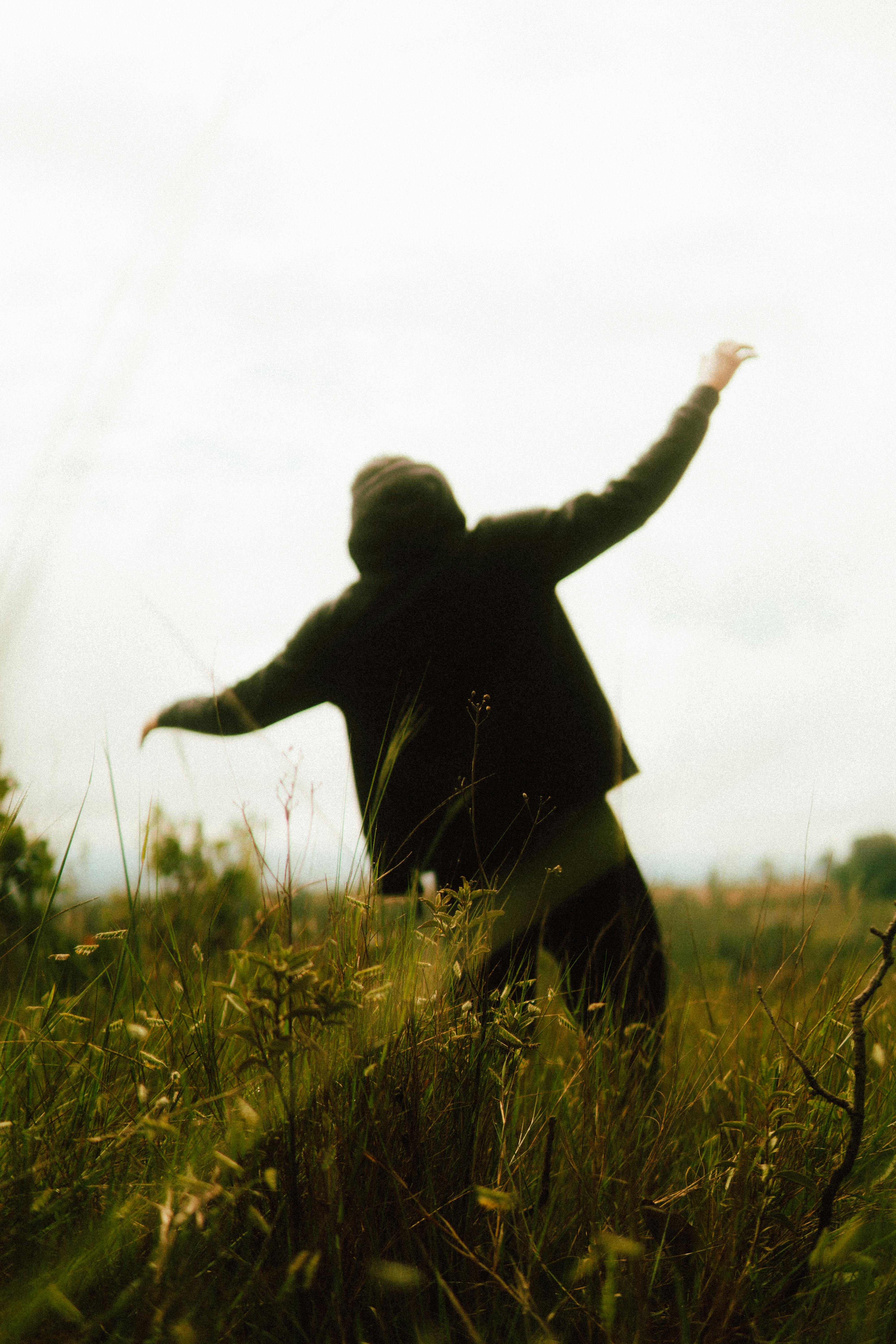ingyenes Egy titokzatos alak egy mezőn, sziluettje az alkonyati égbolt előtt rajzolódik ki, szabadságot és kalandvágyat sugározva. Stockfotó