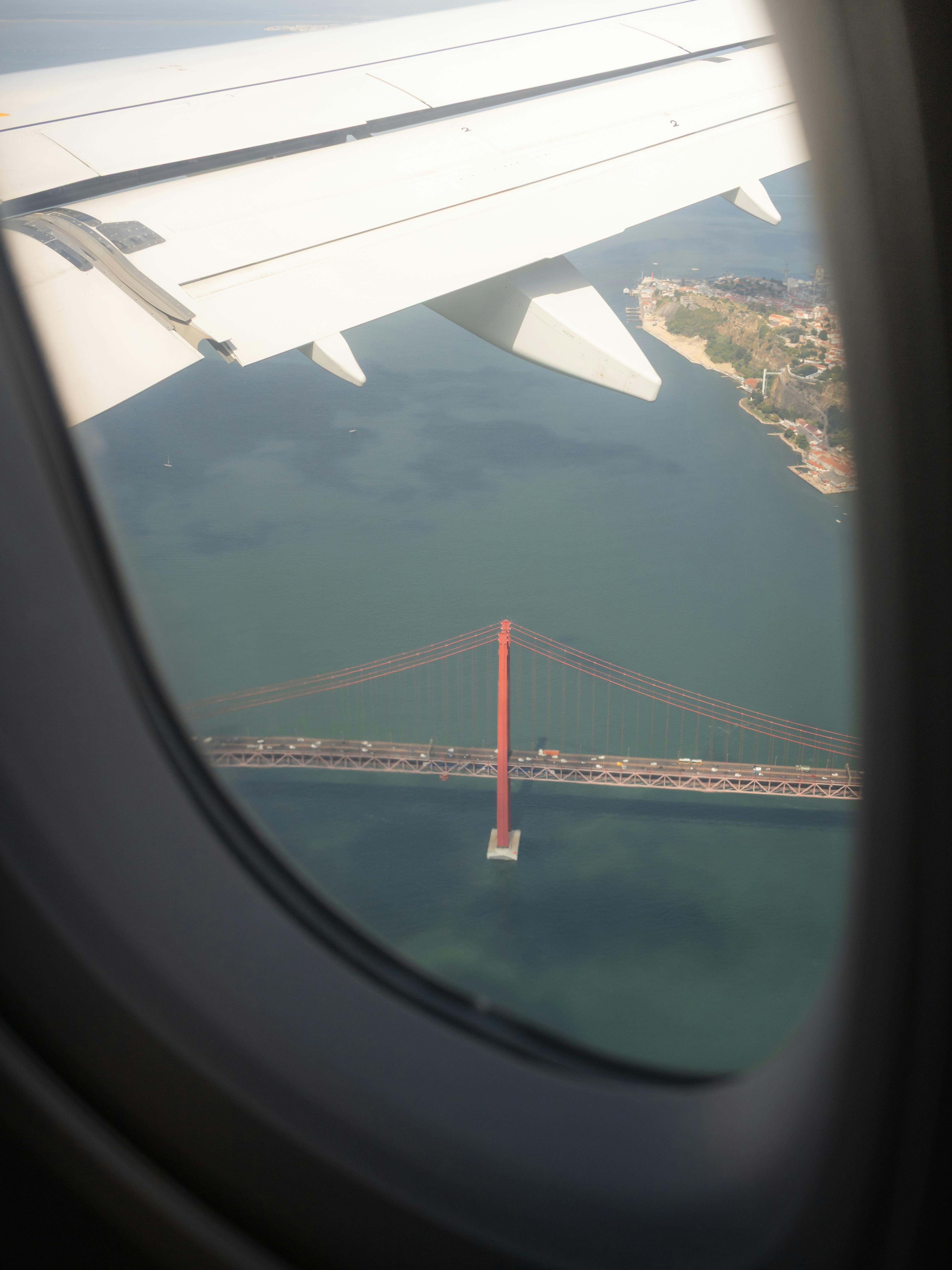 Gratis En fantastisk luftfoto av Lisboas ikoniske Ponte 25 de Abril-bro sett gjennom et flyvindu. Arkivbilde