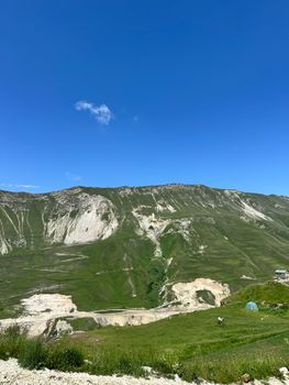 Expansive view of lush green hills and blue sky in summer, capturing the essence of untouched nature.